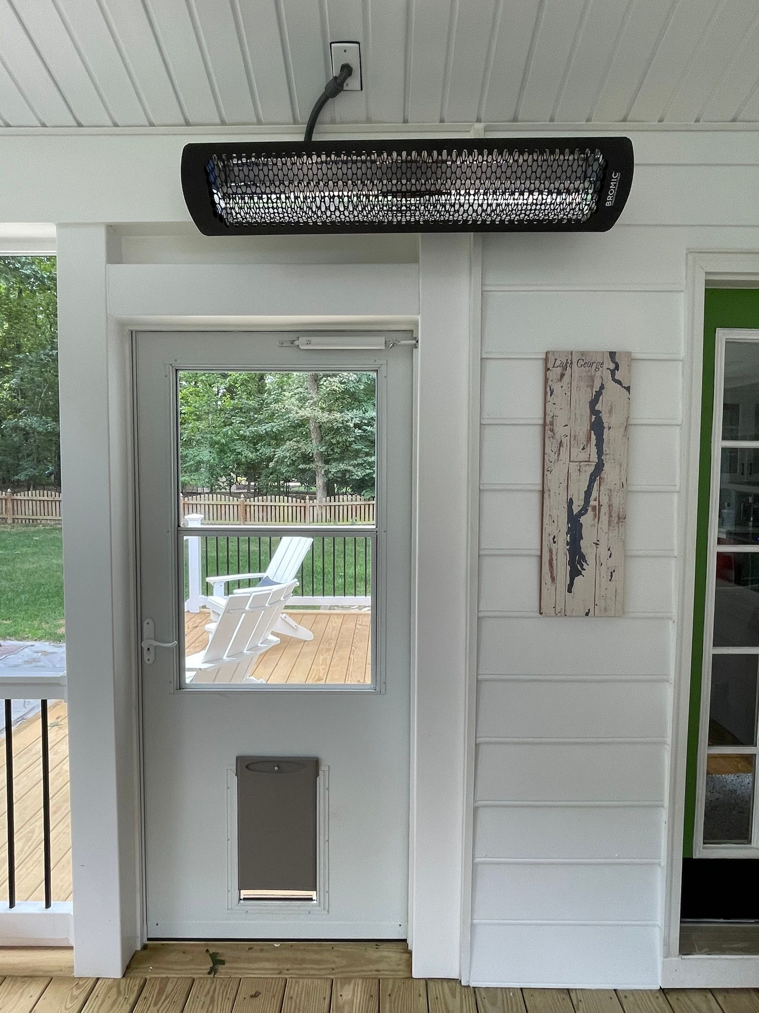 White exterior door with a small window under a black light fixture on a porch.