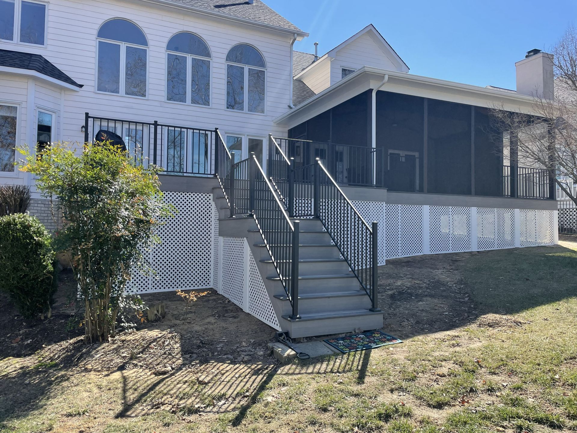 Two-story house with front steps, black railings, and a covered porch with white lattice skirting