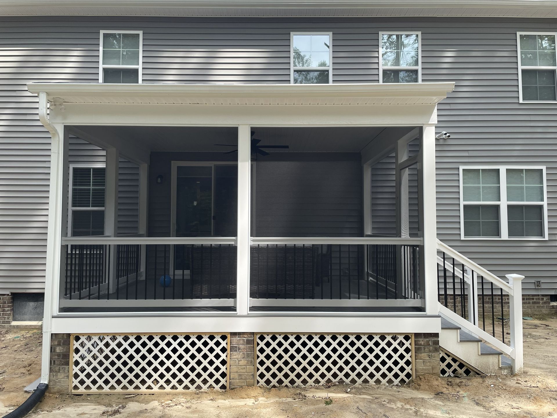 Back porch with gray siding, white railings, and lattice skirting on a house
