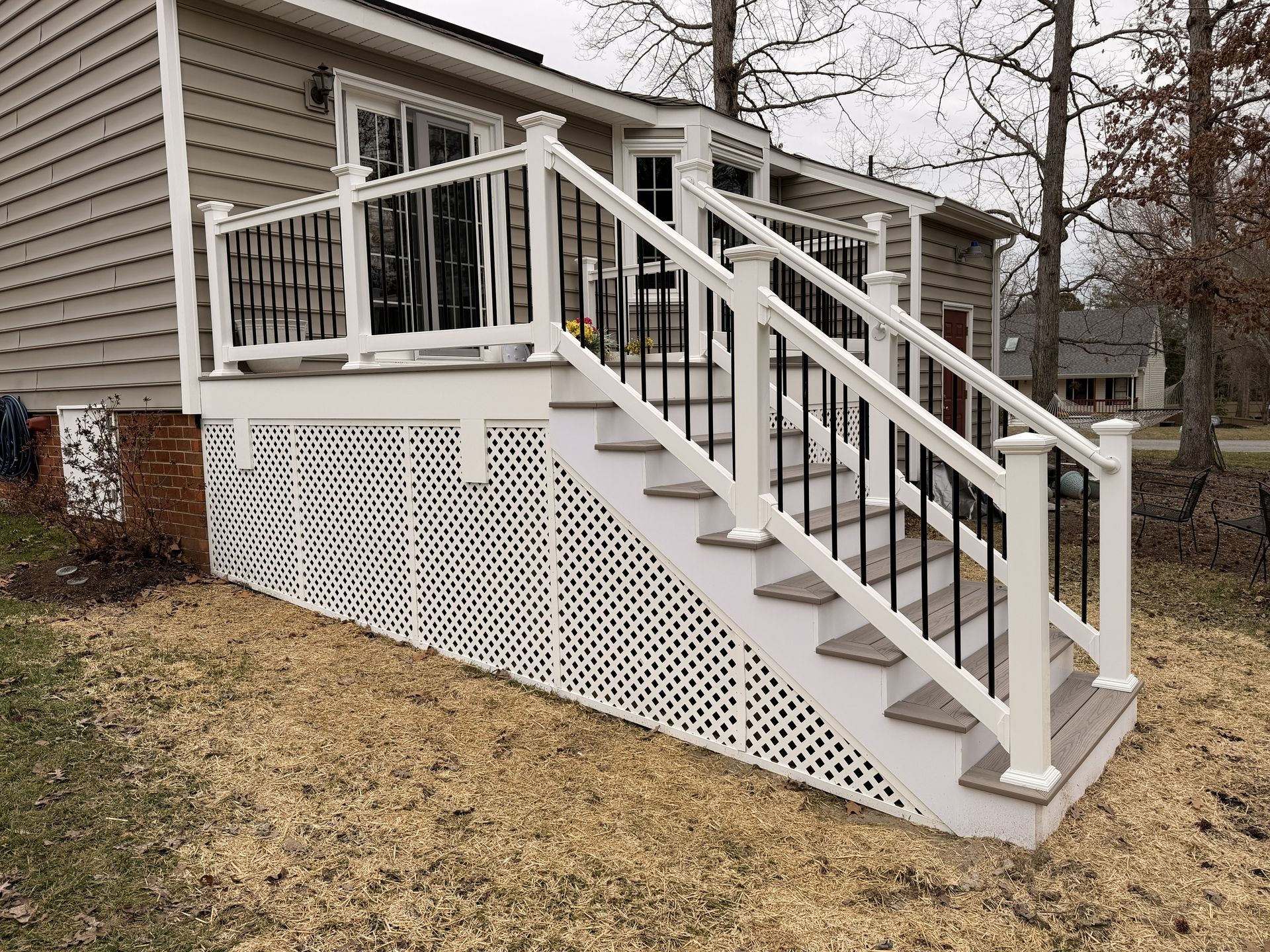 White wooden staircase with railing and lattice skirting on the side of a house