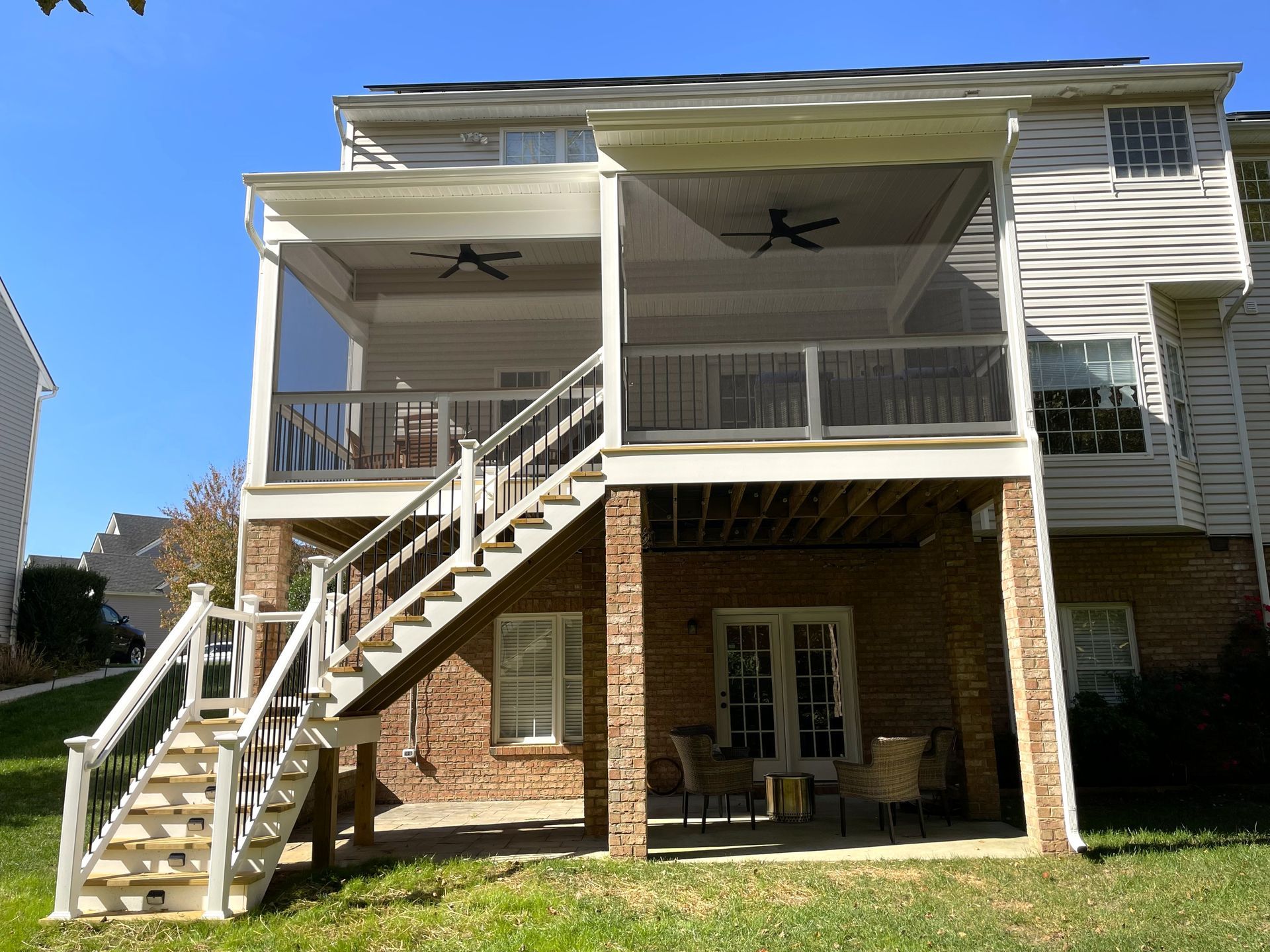 Two-story house with raised porch, white stairs, brick lower level, and ceiling fans underneath