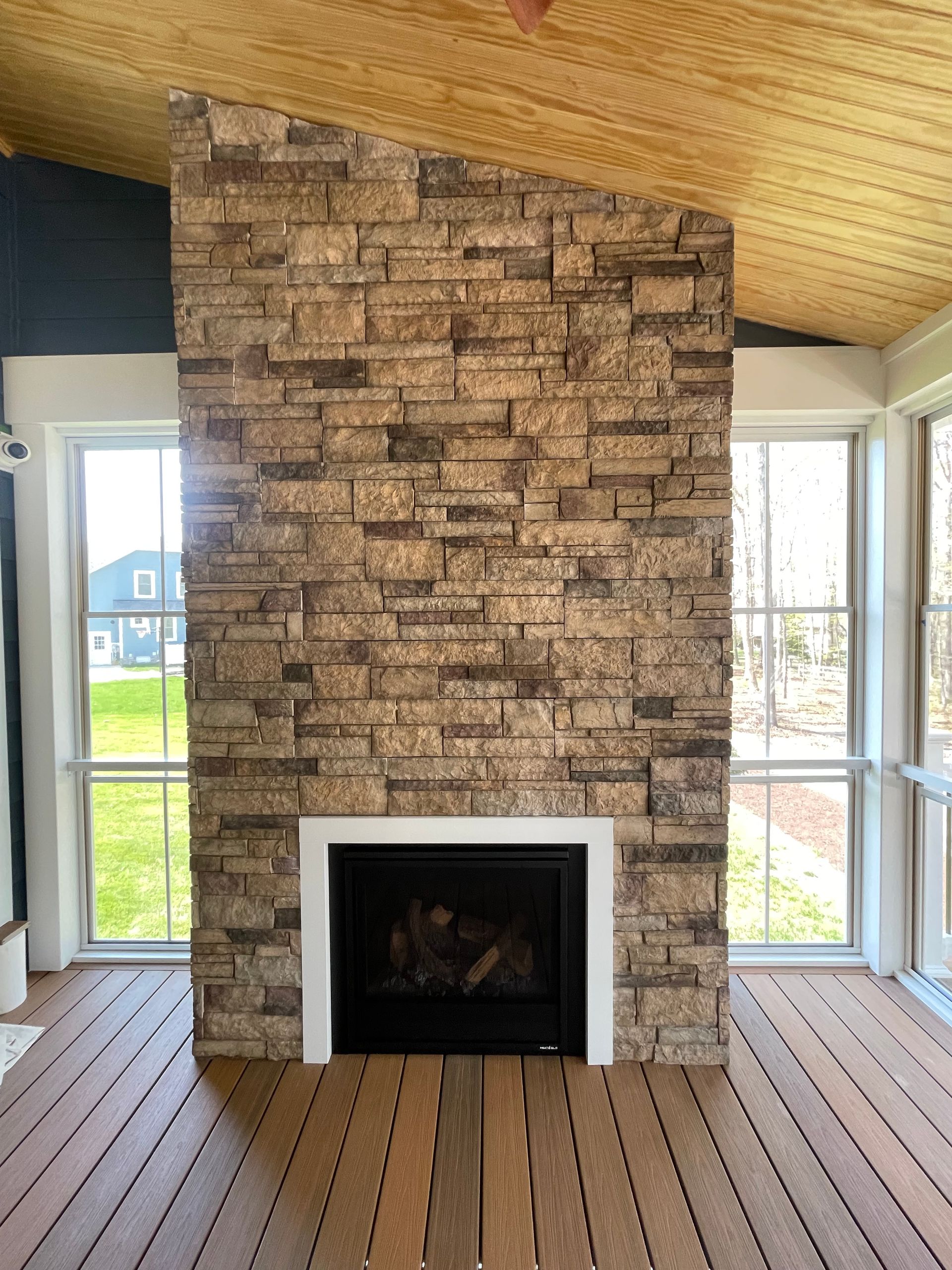 Living room with central brick fireplace, white mantel, wood floor, and large windows on either side