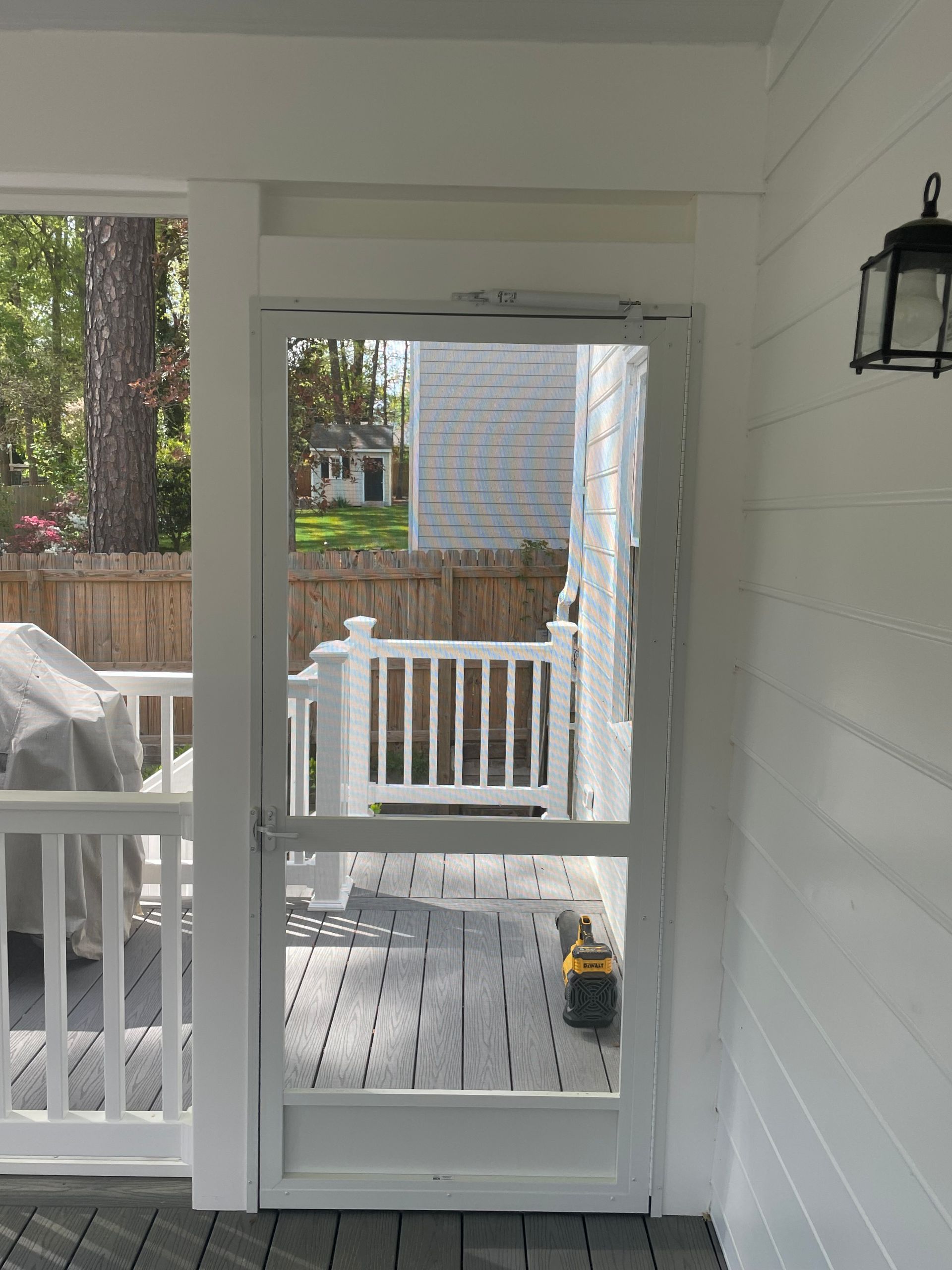 Porch with white screened door, railing, and patio furniture visible outside.