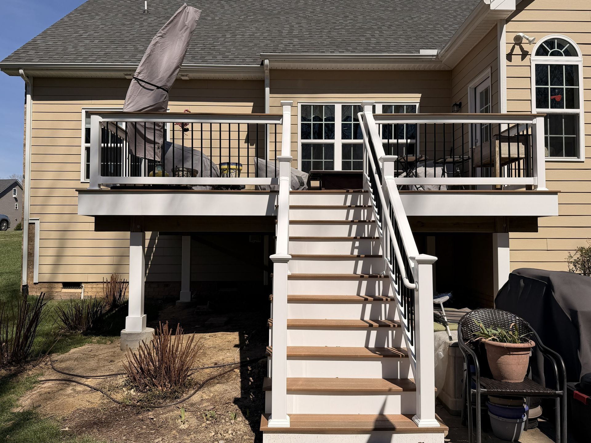 Back deck with white railings, central stairs, and patio furniture on a beige house