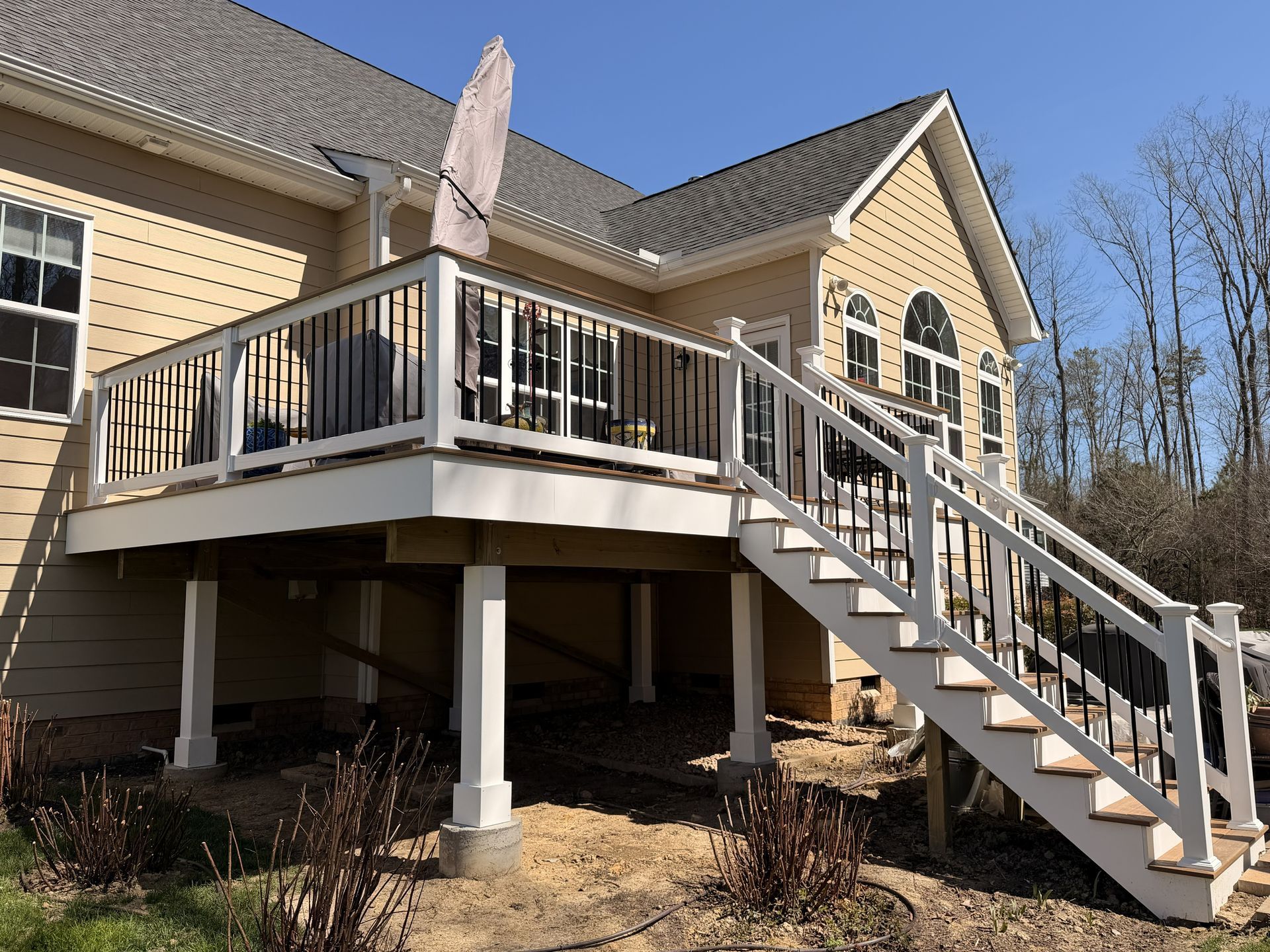 House exterior with raised deck, stairs, and white railings on a brick home