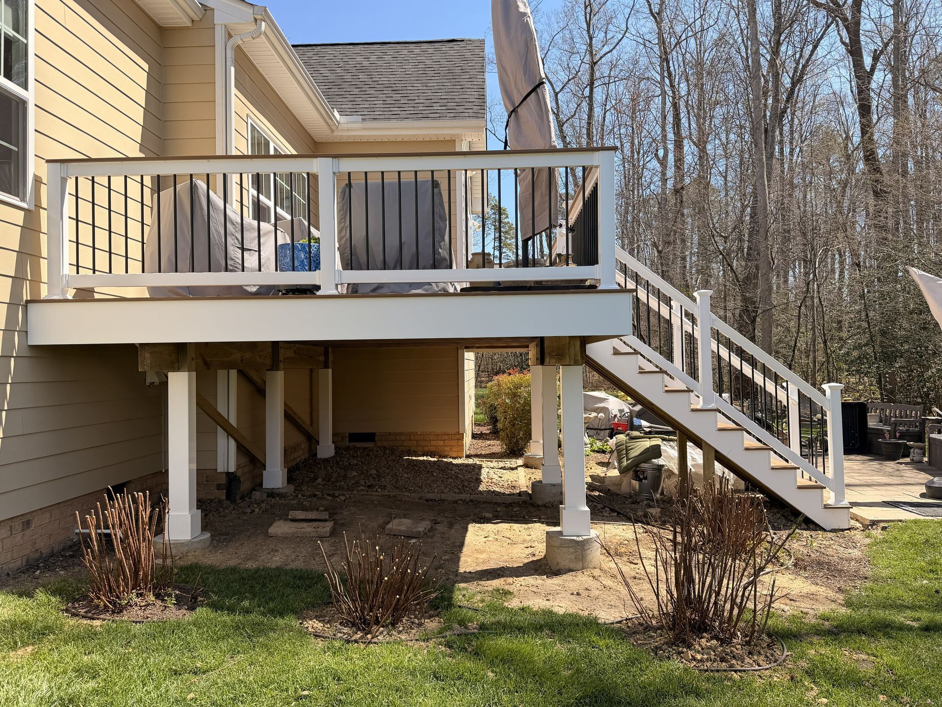 House deck with white railings and stairs leading down to a yard and trees.
