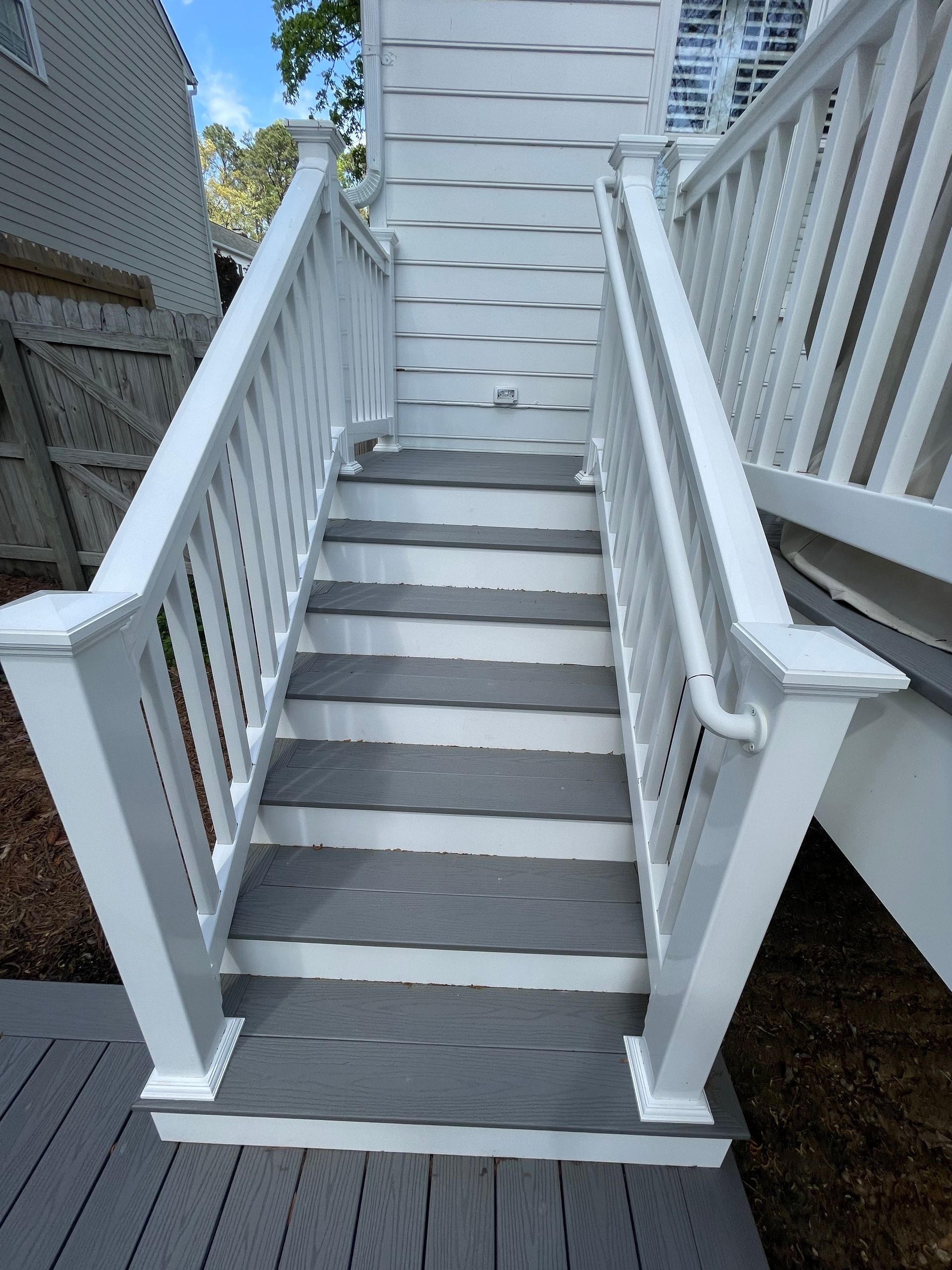 White outdoor stairway with railings leading up to a raised doorway between buildings