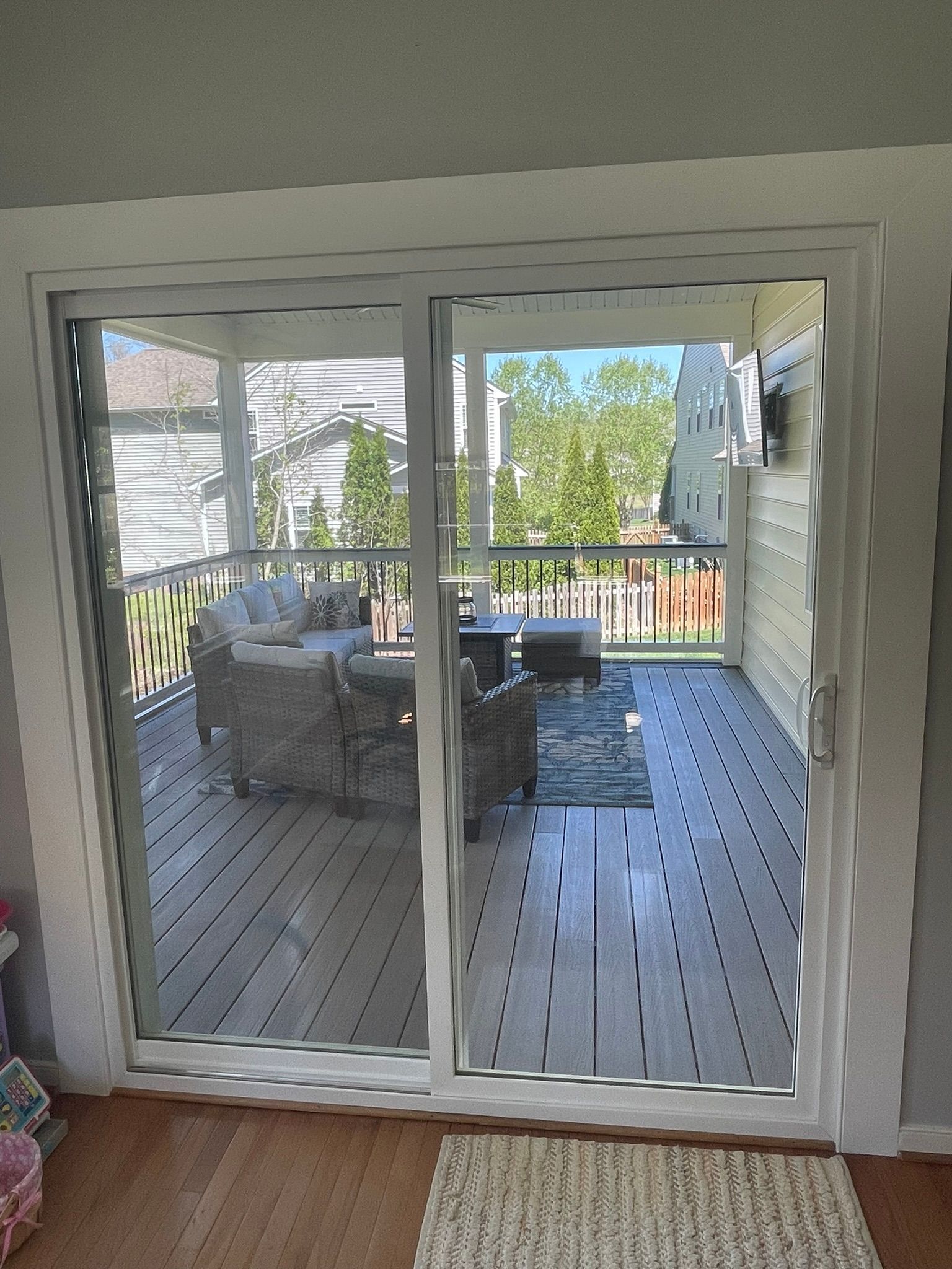 Sliding glass doors open to a gray deck with outdoor seating under a covered patio.