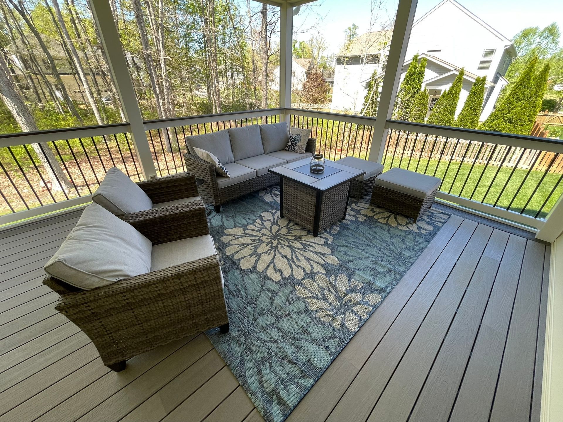 Patio seating area with wicker chairs, cushions, and a coffee table on a patterned outdoor rug.