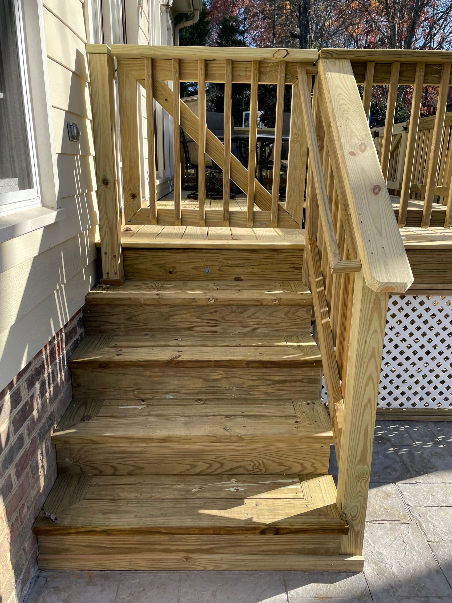 Wooden front steps with railing leading up to a porch outside a house