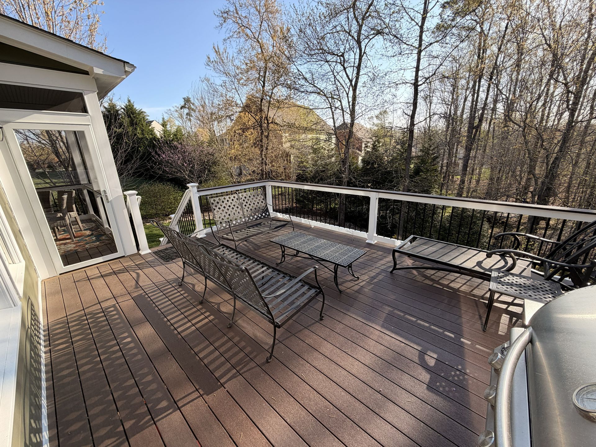 Deck with two lounge chairs, white railing, and autumn trees in the background.