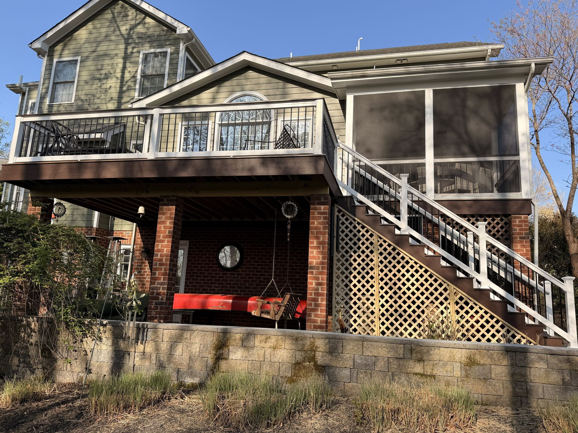 Two-story house with a screened porch, front balcony, and exterior staircase under a blue sky