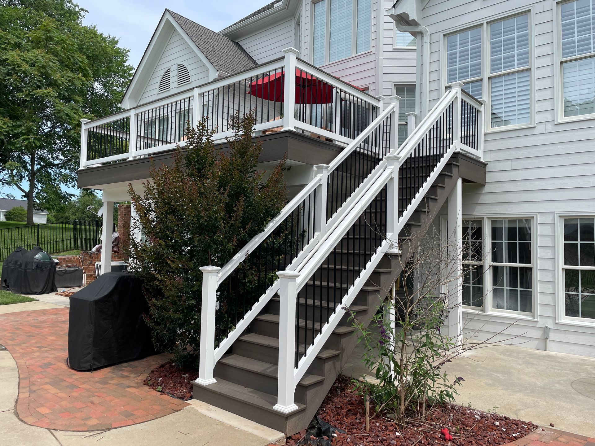 House exterior with white stairs leading to a porch and red patio umbrella