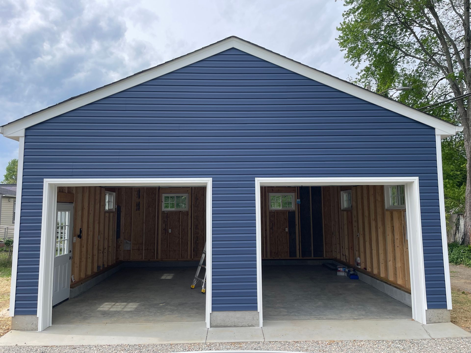 Blue two-bay garage with open doors and unfinished interior, viewed from the front
