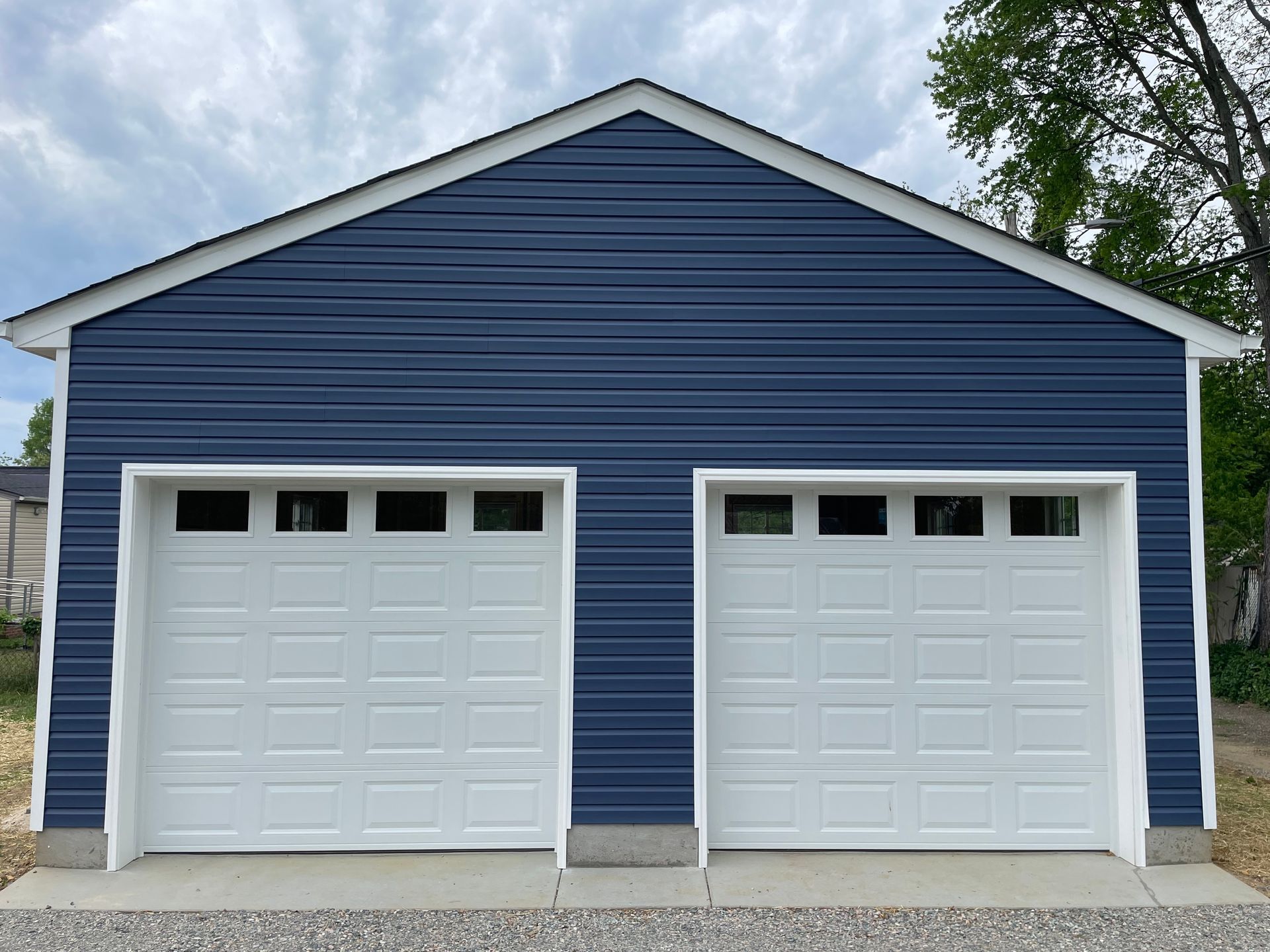 Blue detached garage with two white doors and three small windows on each door