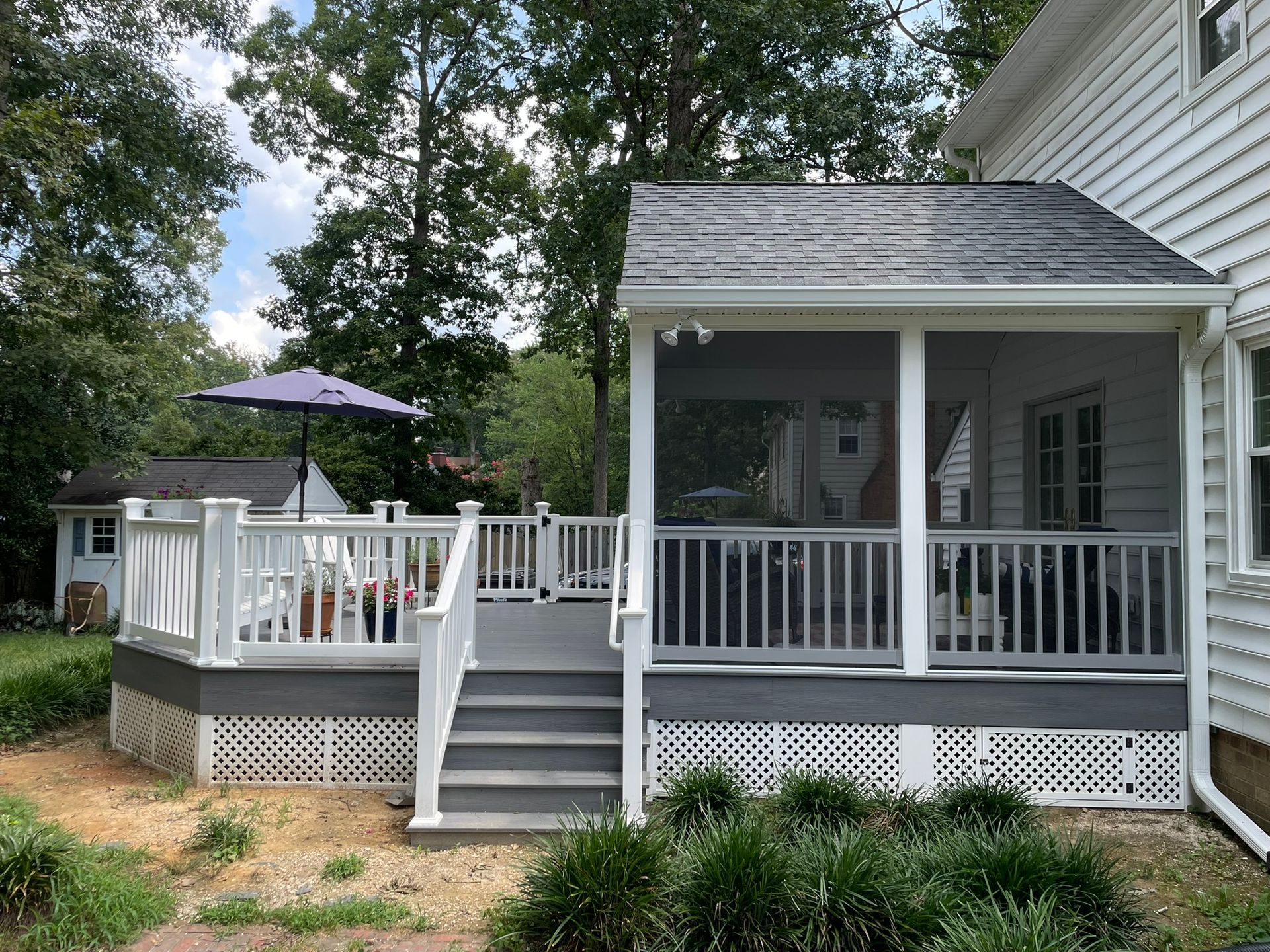 White-railed backyard deck with stairs, patio umbrella, and gray house siding