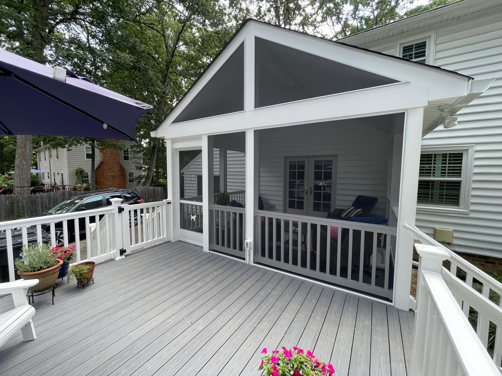 Back deck with white railings, gray flooring, and a screened porch under a peaked roof
