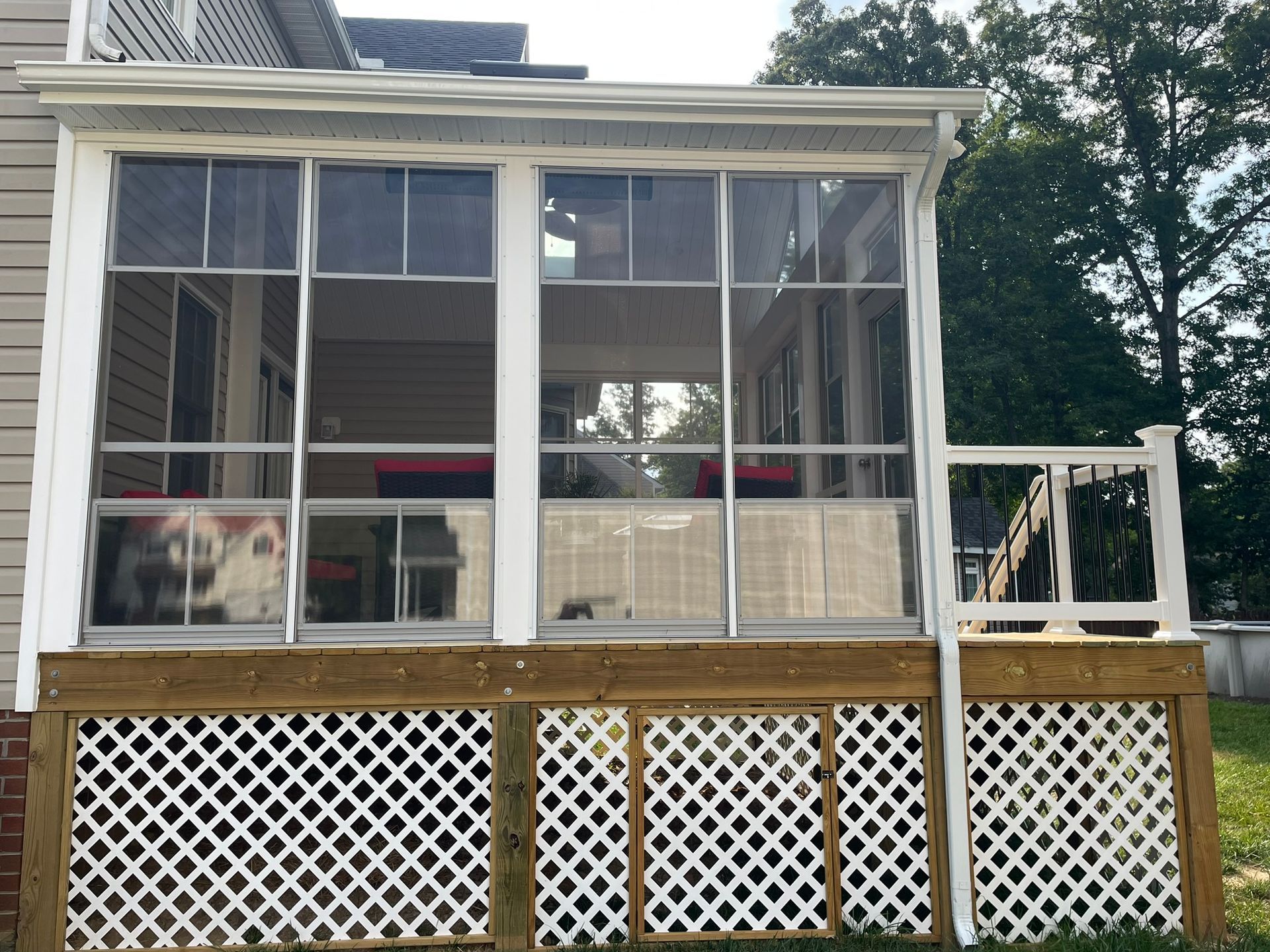 Screened porch with white lattice railing and a small pet behind the left window.