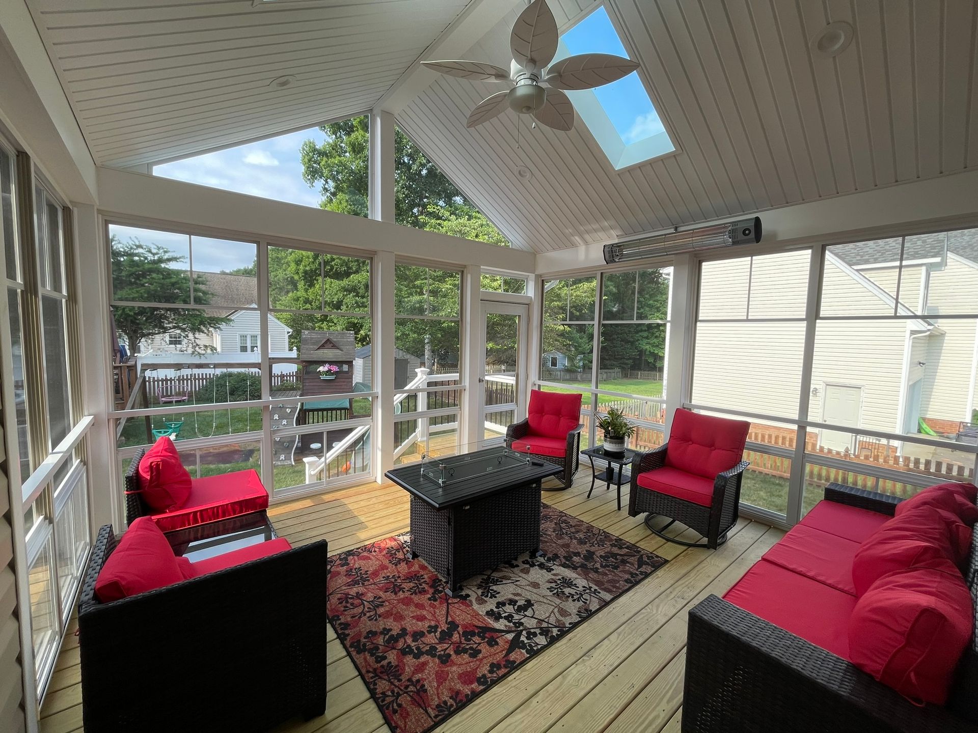 Covered porch with red cushioned seating, coffee table, ceiling fan, and view of the street beyond.