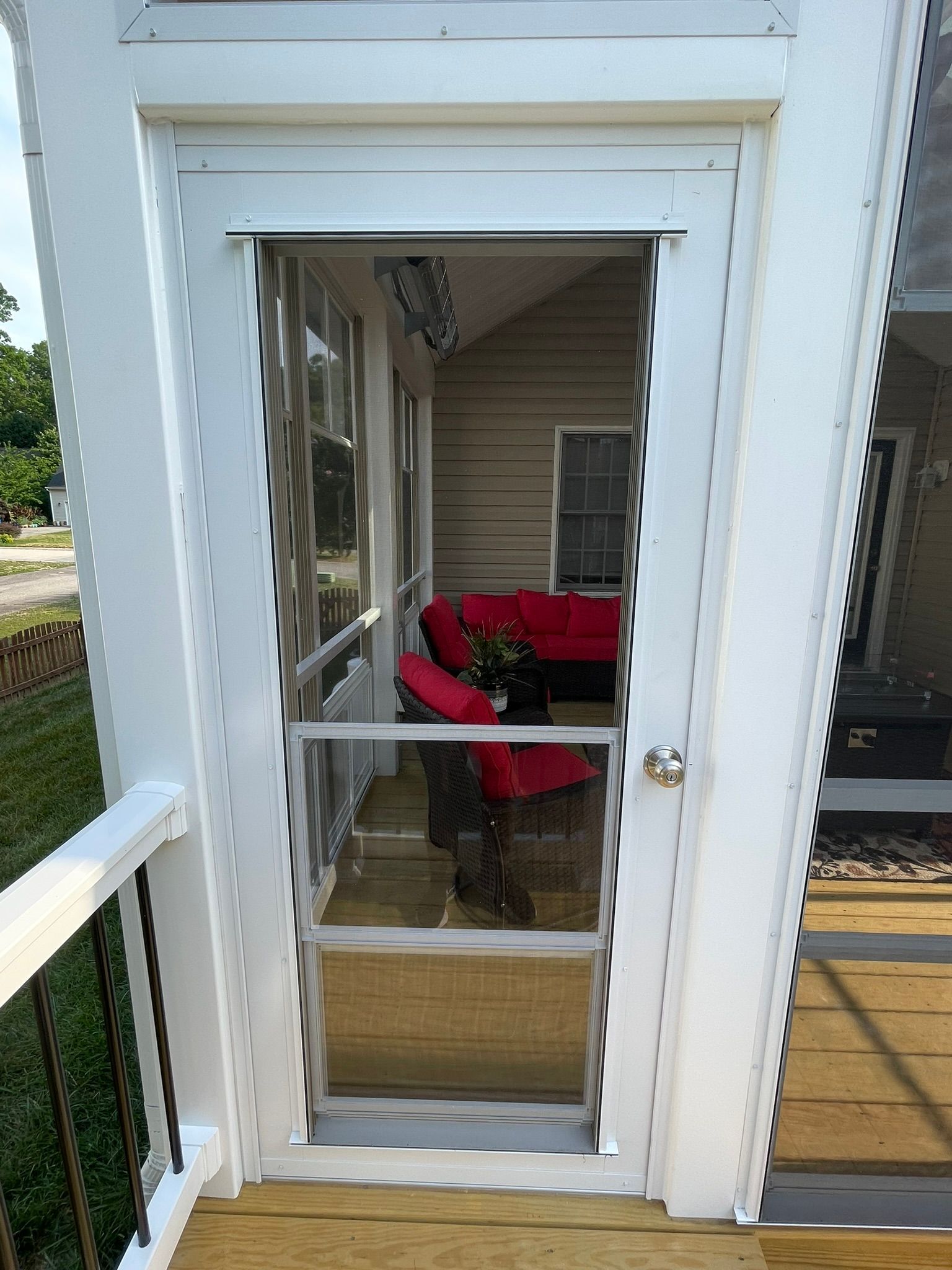 Person in red shirt bending over near a glass door on a porch.