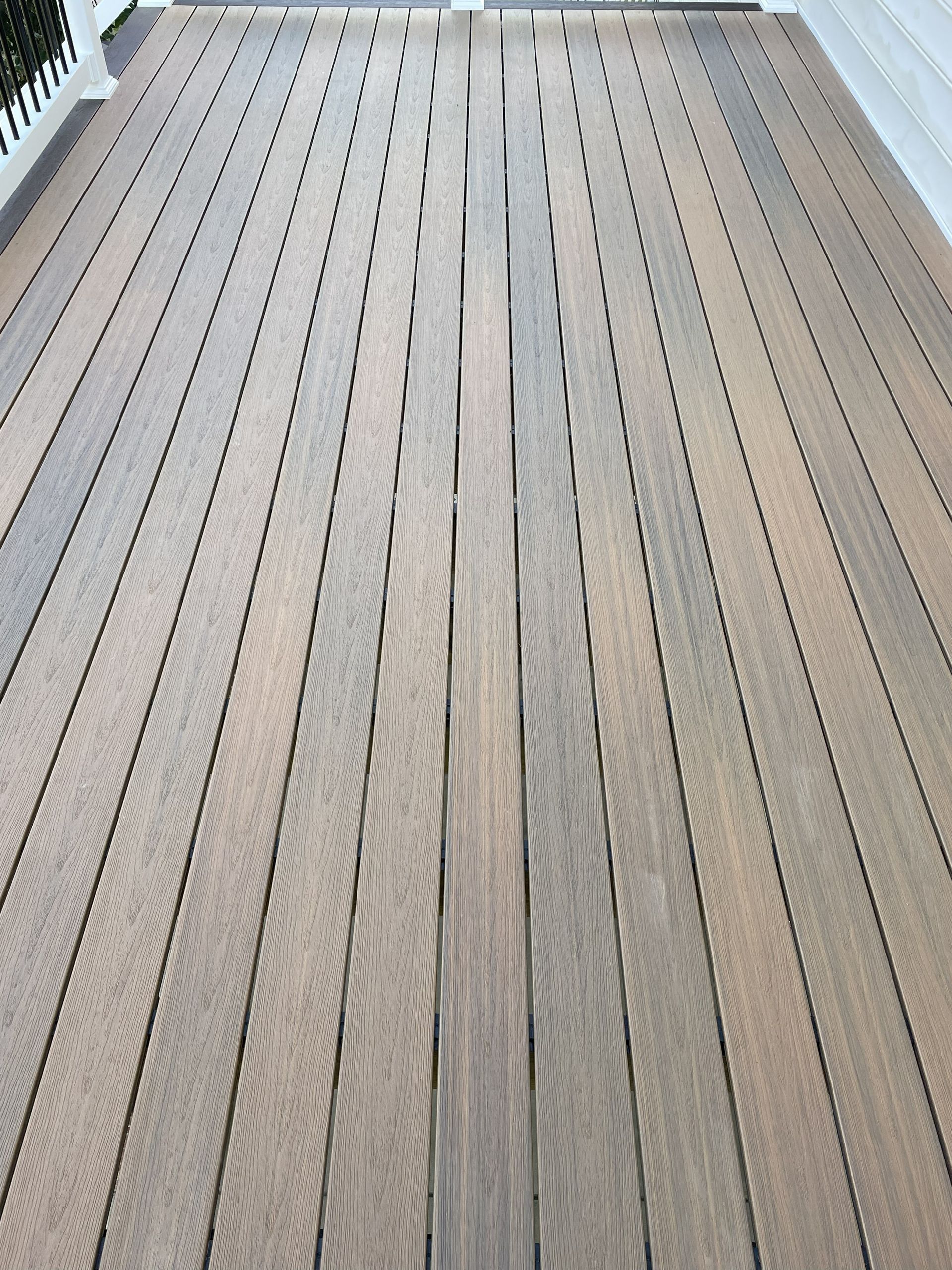 Wooden deck boards with two rows of black drainage or light slots running down the center
