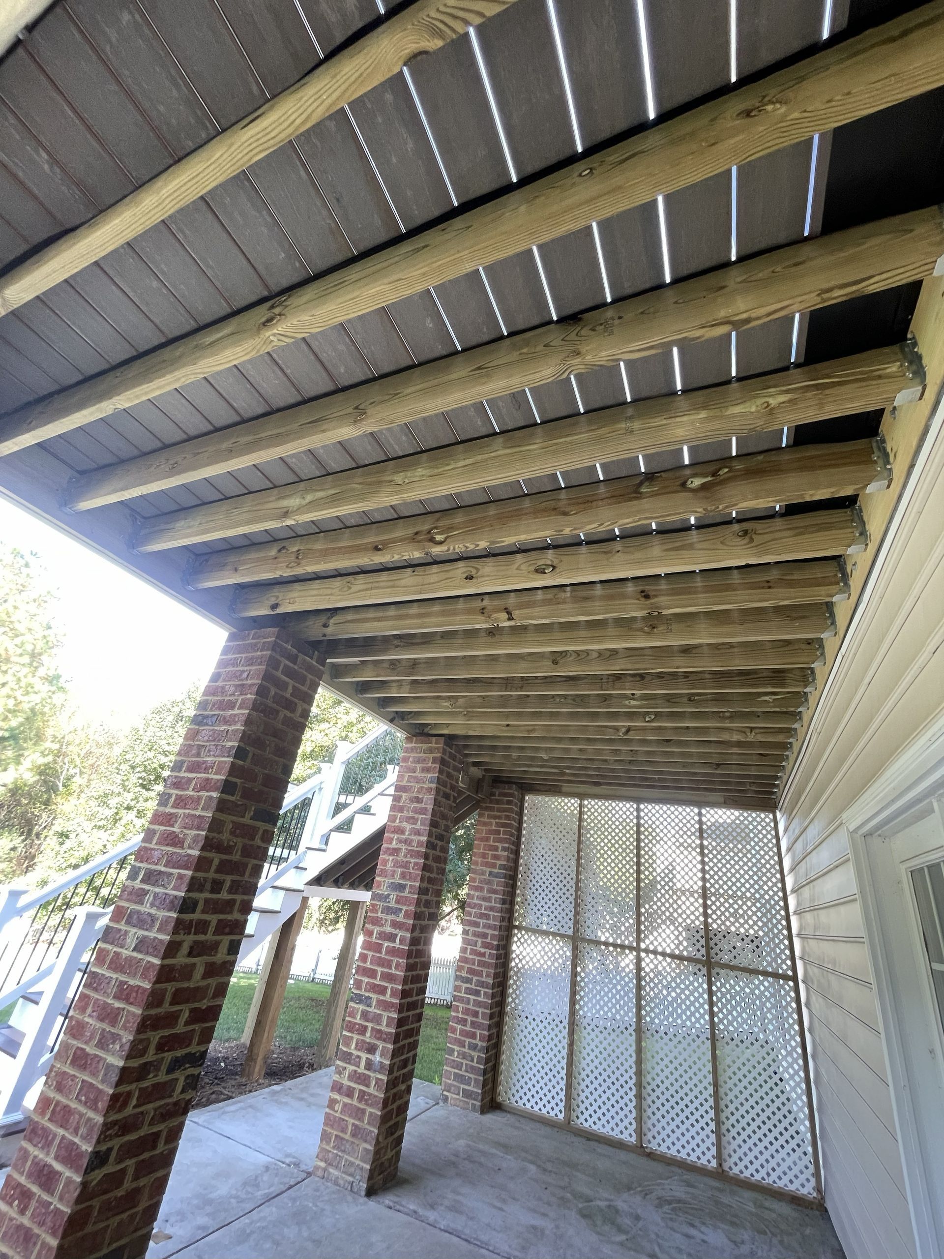 Under a raised wooden deck with brick posts and a white lattice gate, viewed from below.