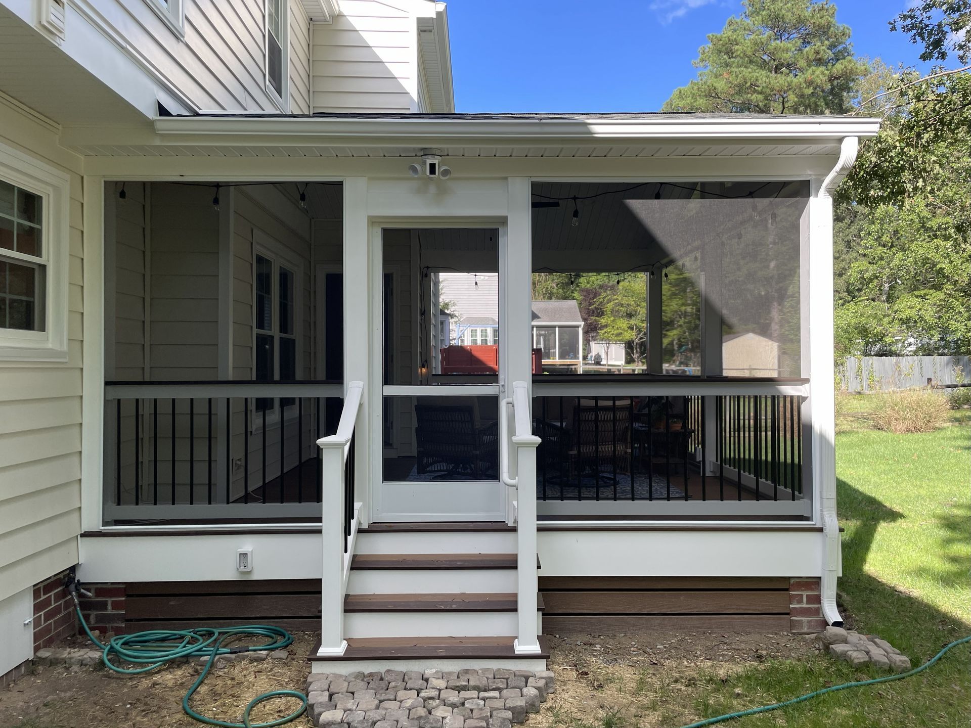 Front porch with white railings, black screens, steps, and a door on a beige house.