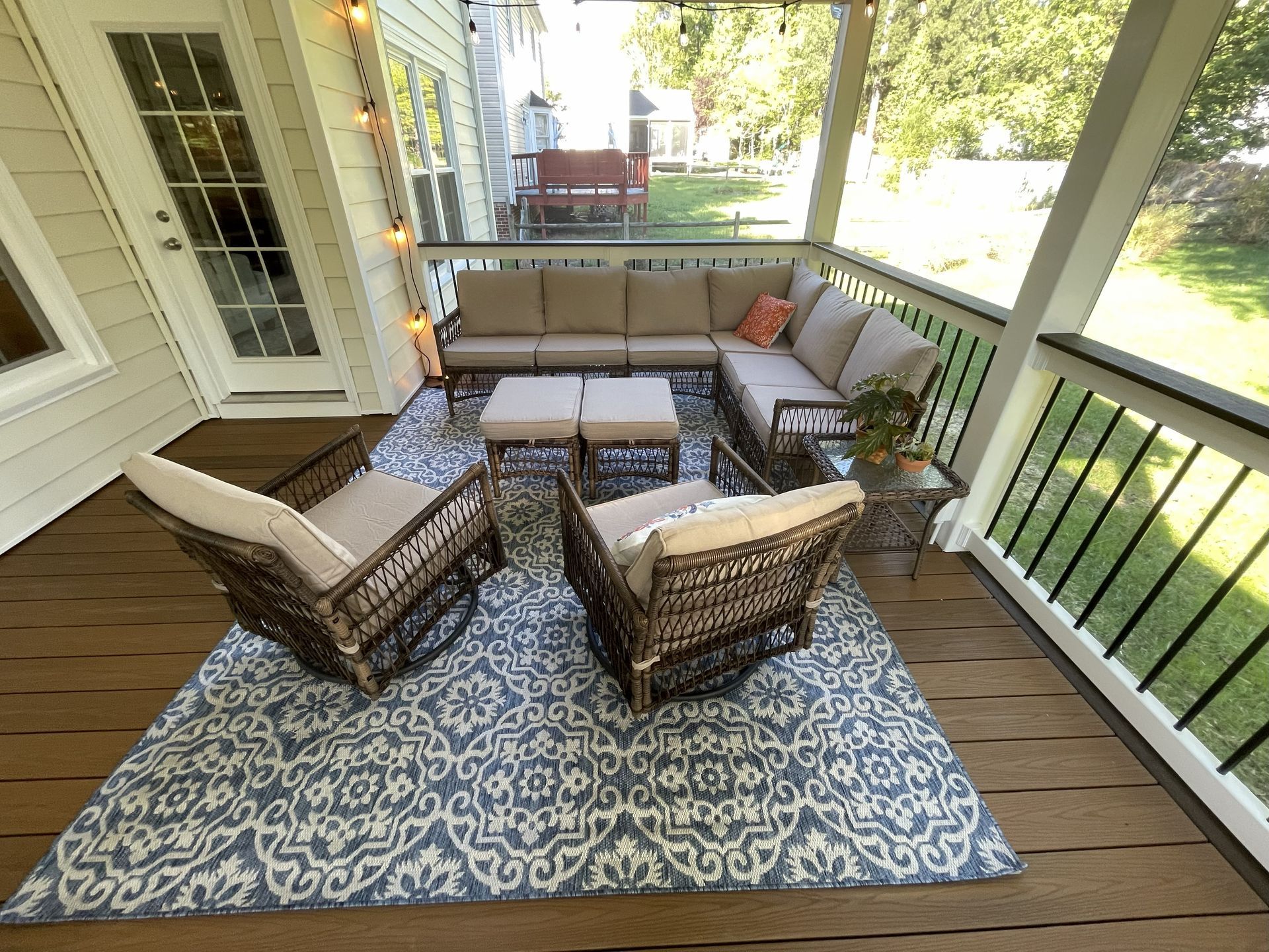 Covered porch with wicker seating around a small table on a patterned outdoor rug.