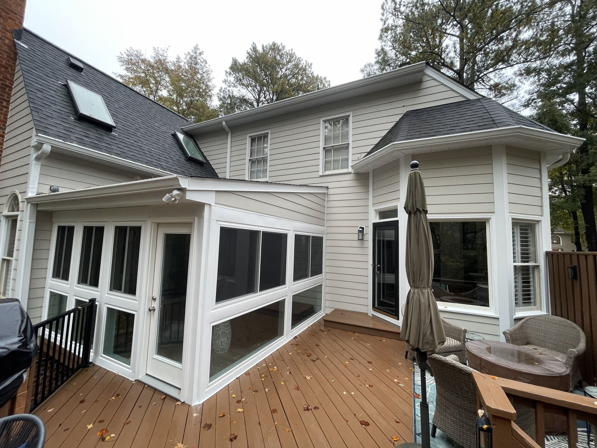 White house exterior with screened porch and wooden deck, seen from the backyard