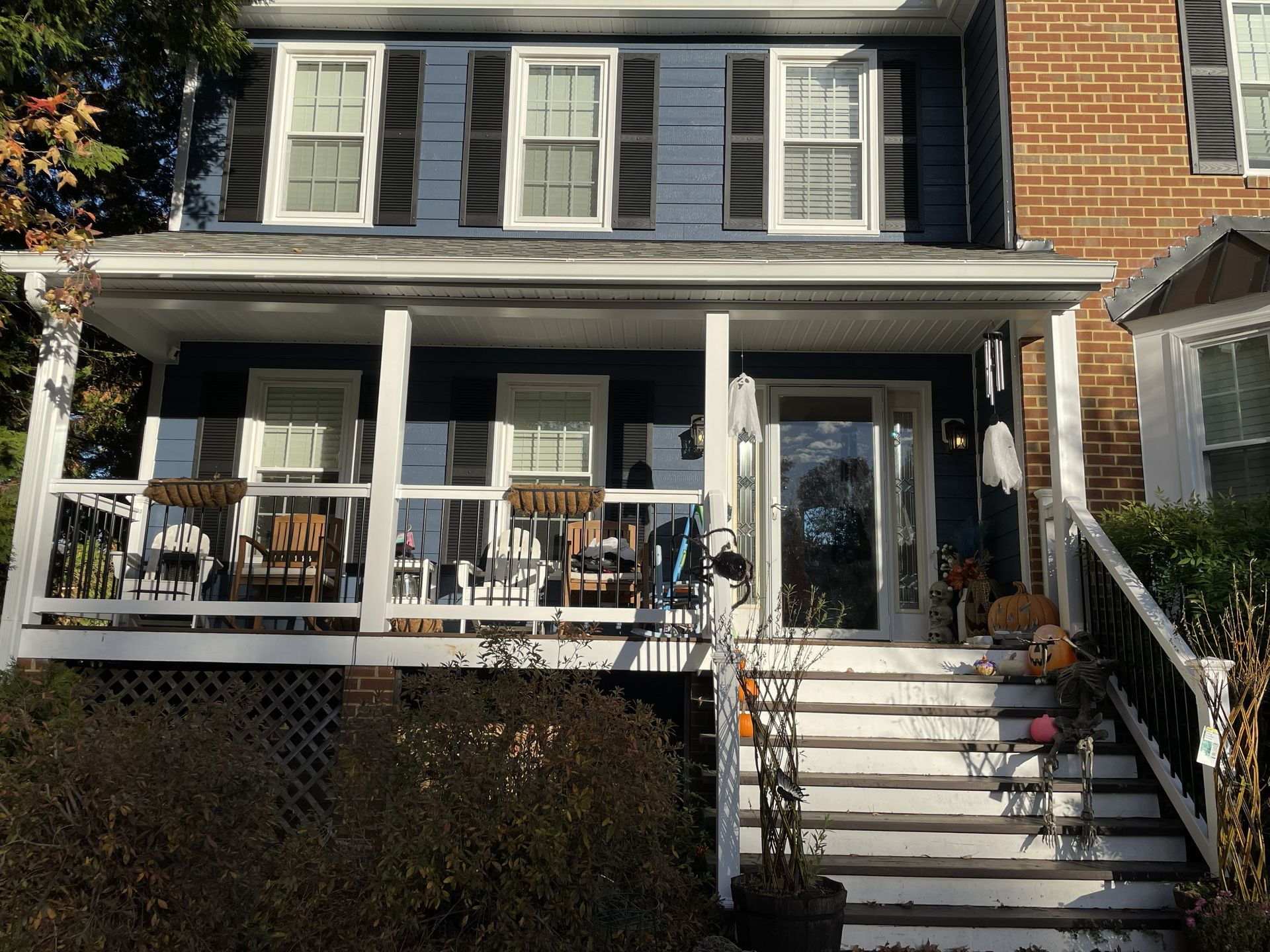 Front porch of a blue house with white columns and stairs leading to the entrance.