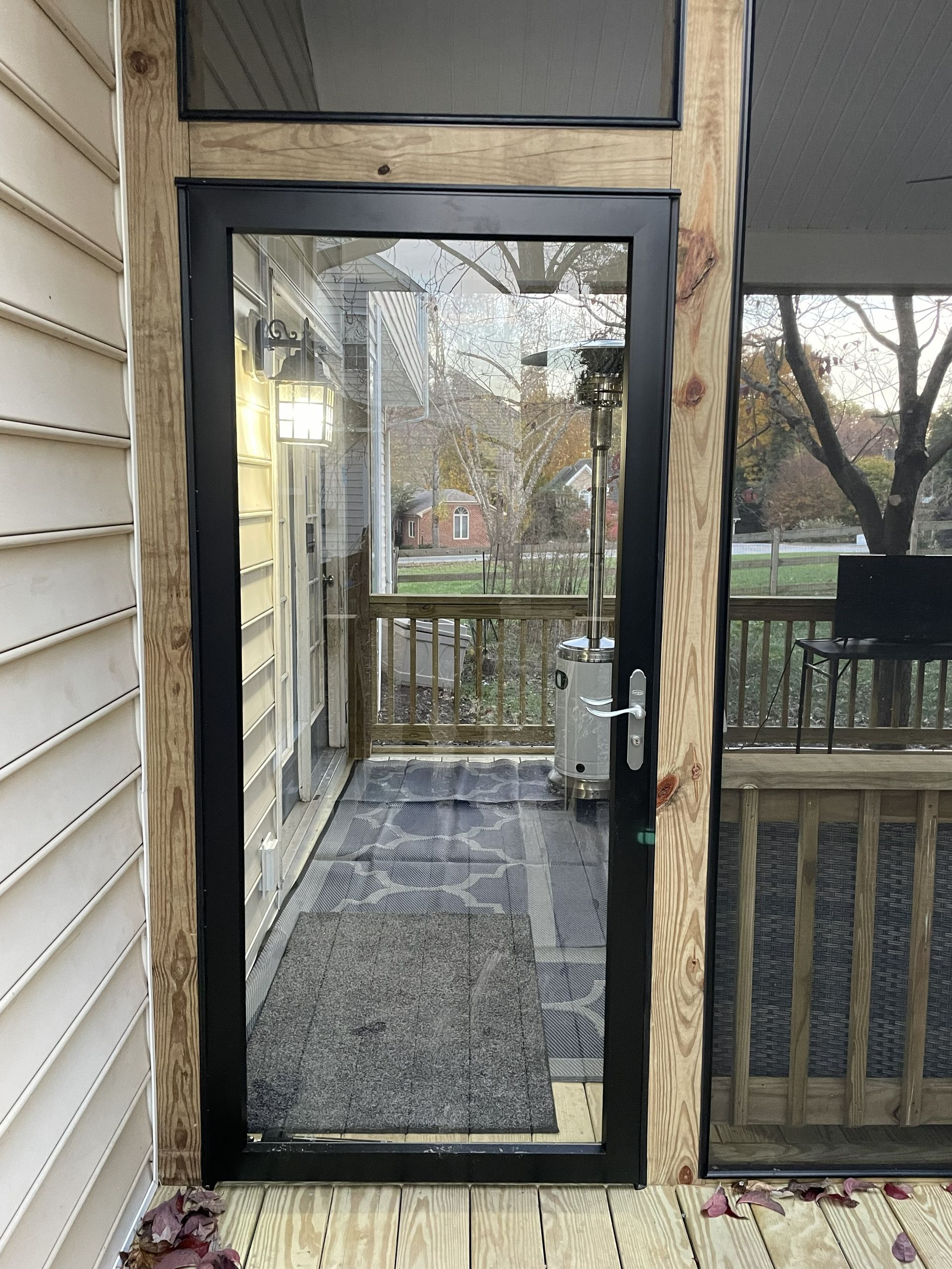 Glass patio door with black frame and backyard view from a covered porch