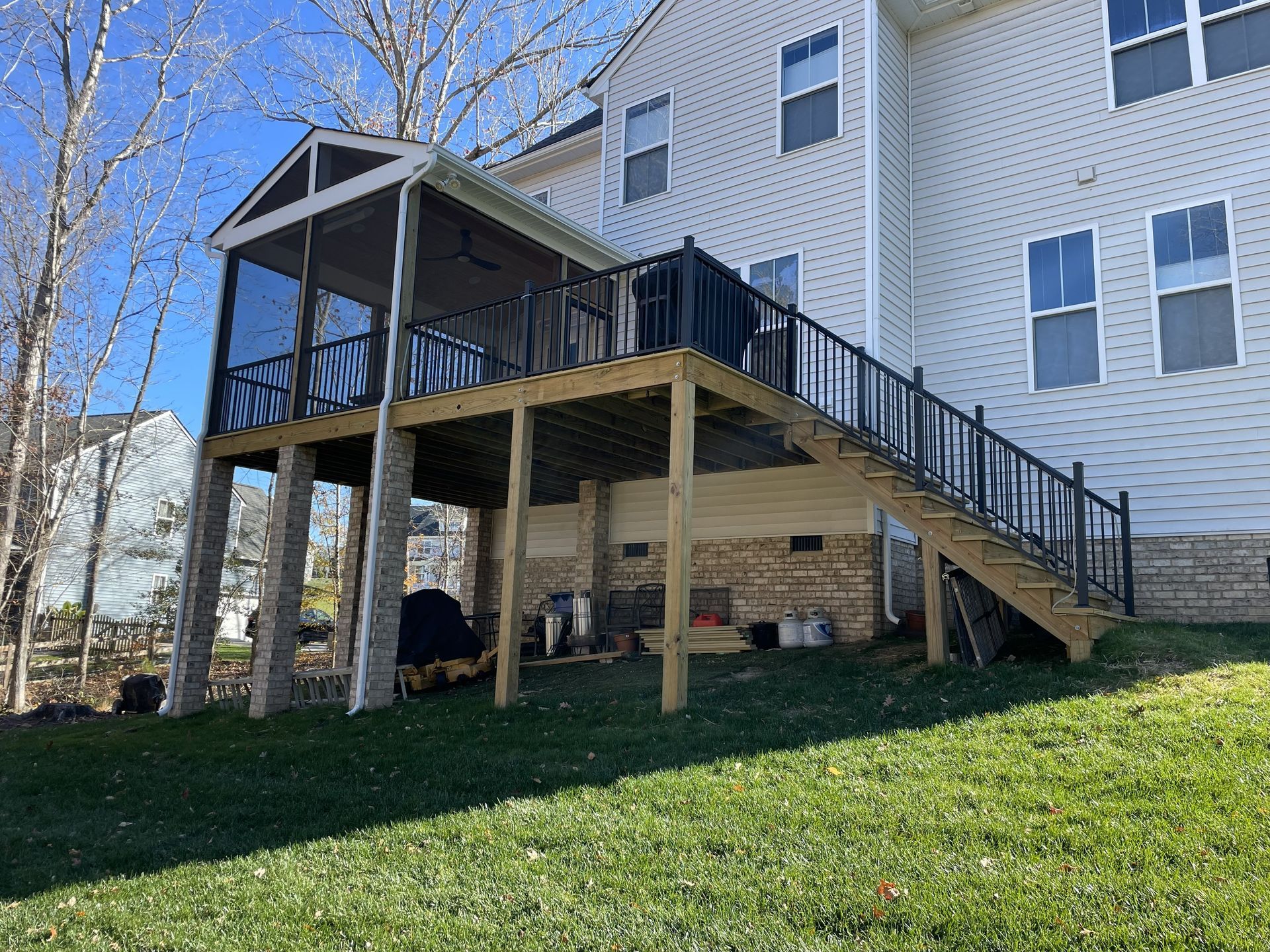 Back deck and stairs on a white house, with a covered patio underneath and grassy yard in front