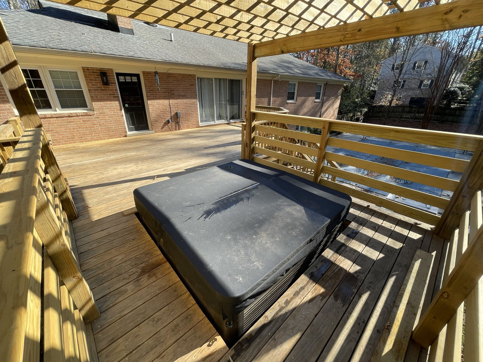 Wooden backyard deck with a pergola and a covered outdoor daybed or hot tub seating area