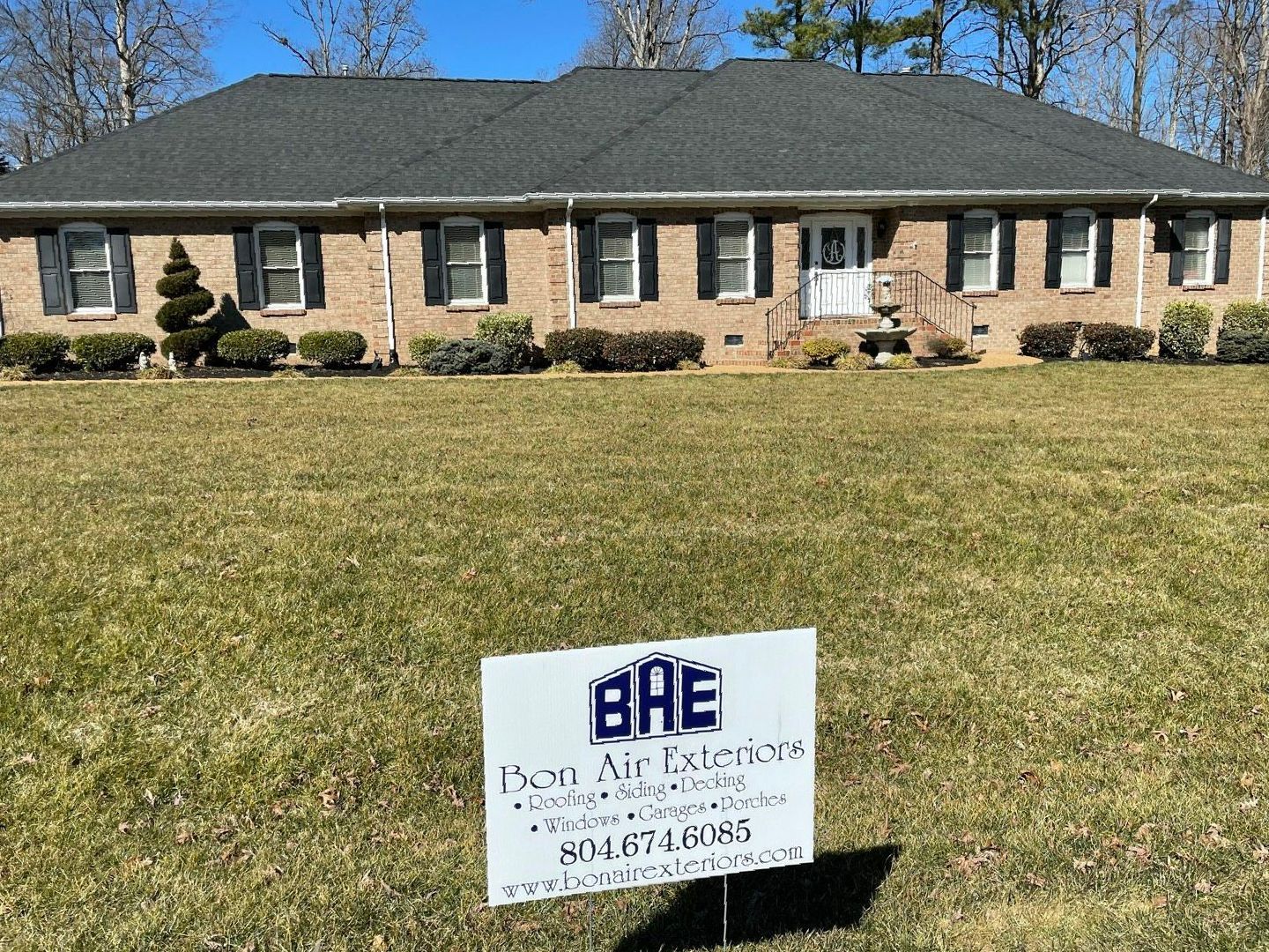Brick ranch house with manicured lawn and a small realtor sign in the front yard.
