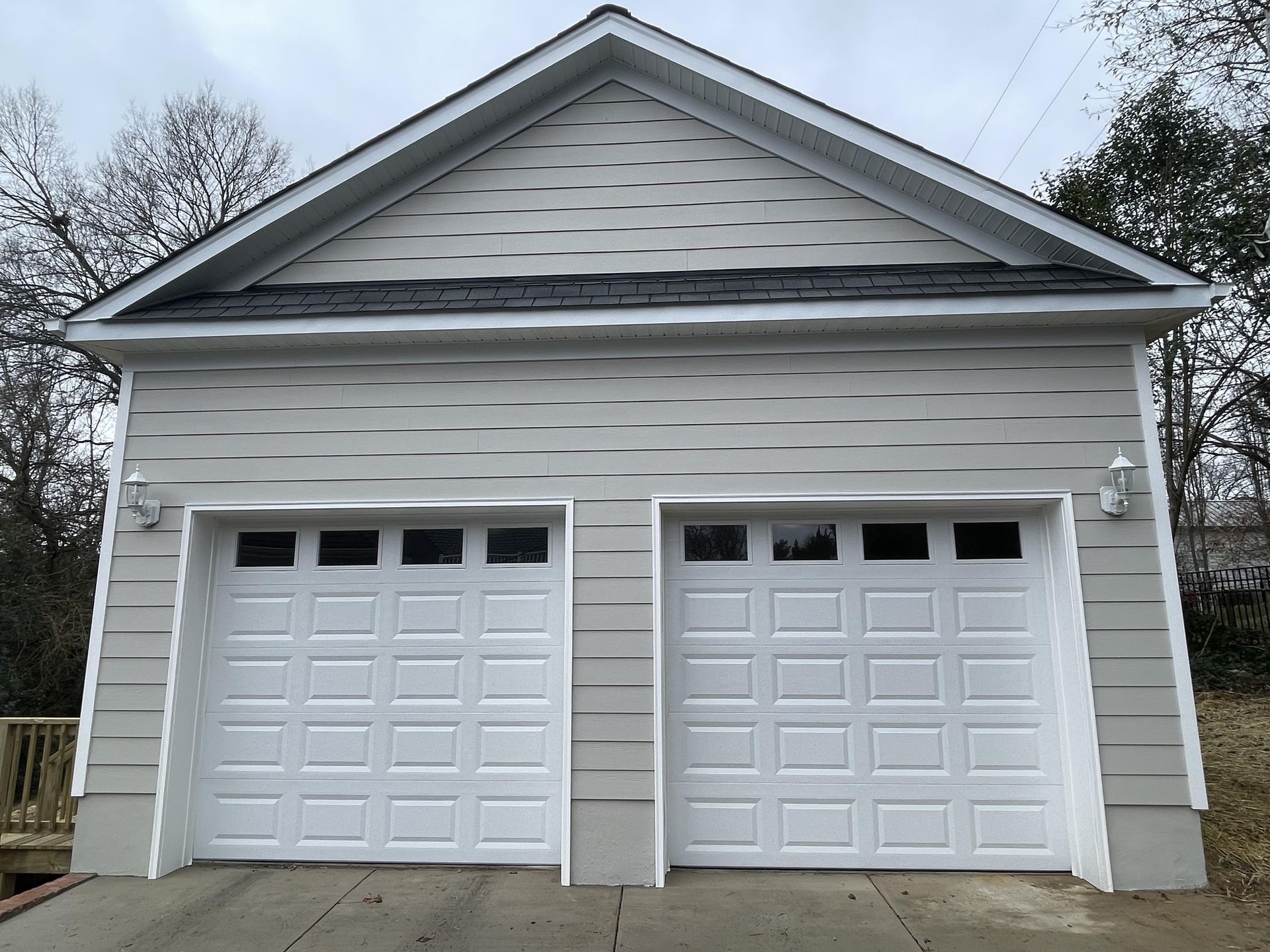 Front view of a white two-car garage with double doors and gray siding