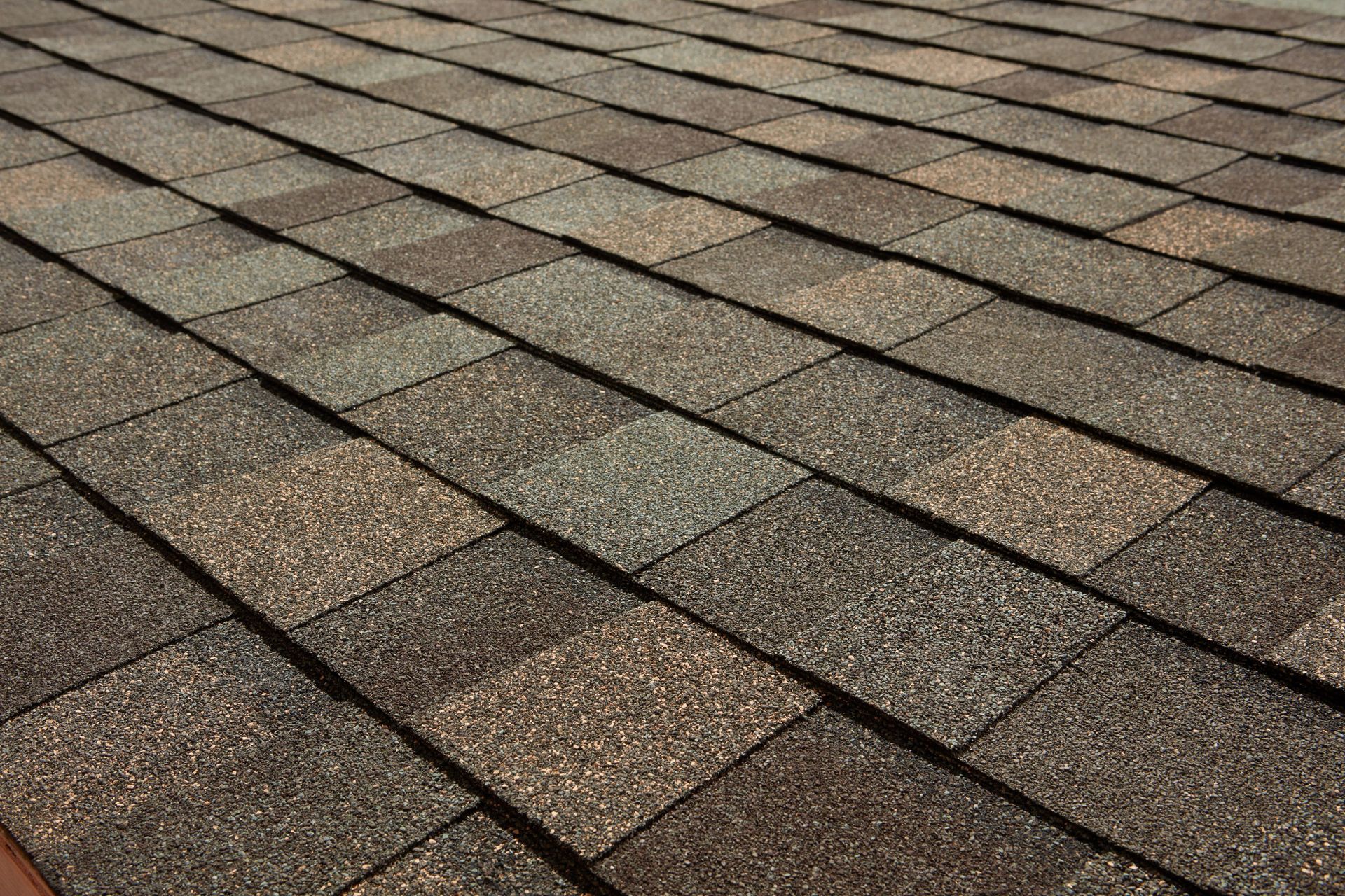 Close-up of brown asphalt roof shingles in overlapping rows
