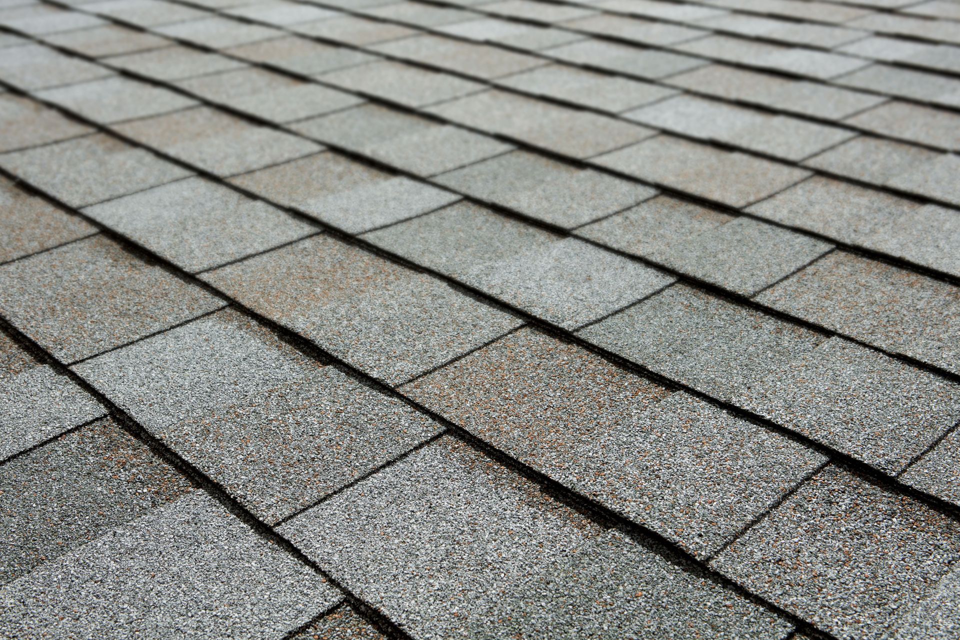 Close-up of weathered gray asphalt roof shingles arranged in overlapping rows
