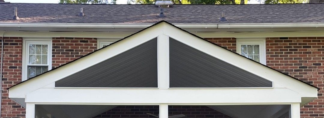 Front gable roof with dark shingles and white trim on a brick house facade