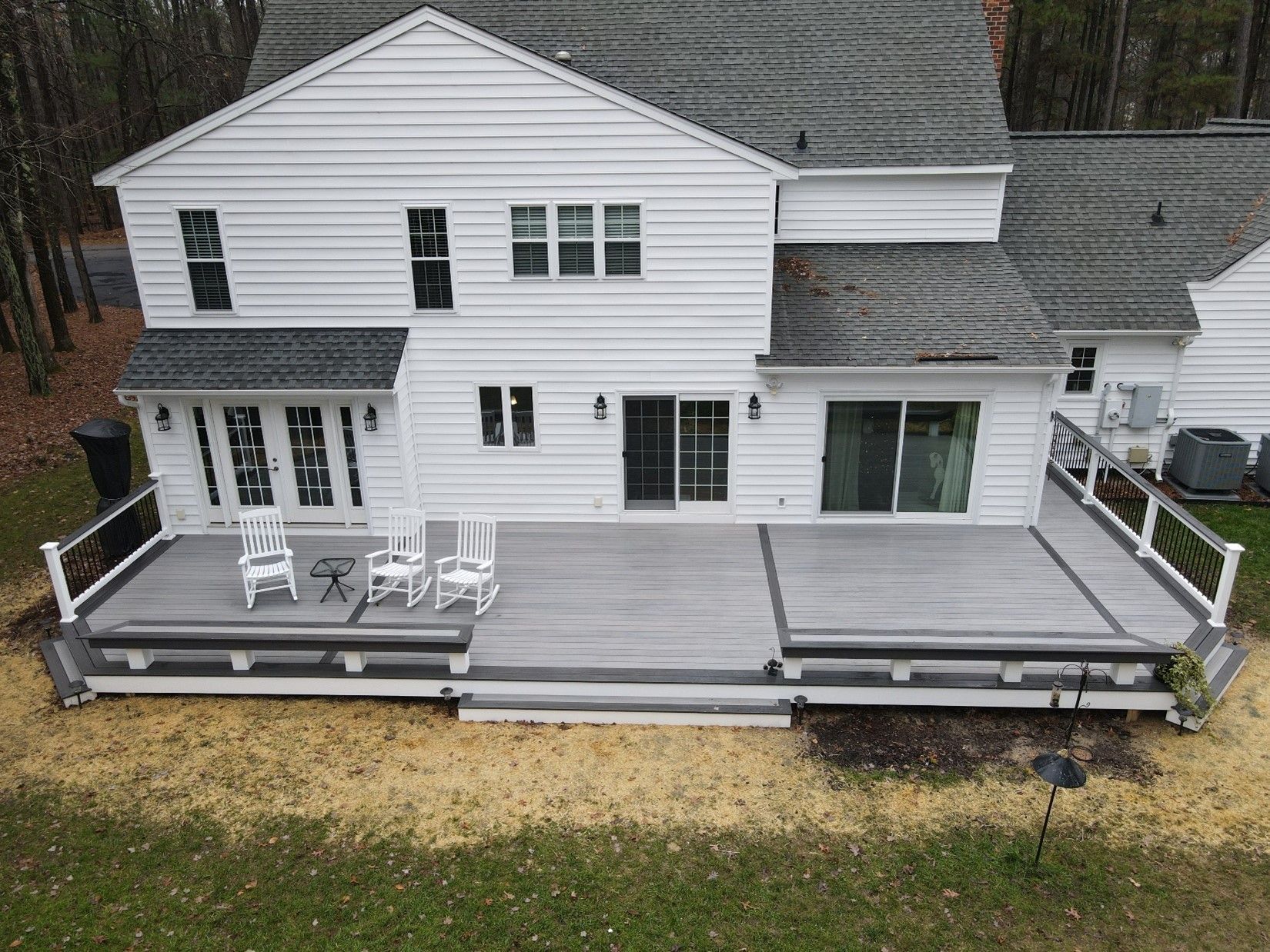 An aerial view of a large white house with a large deck.