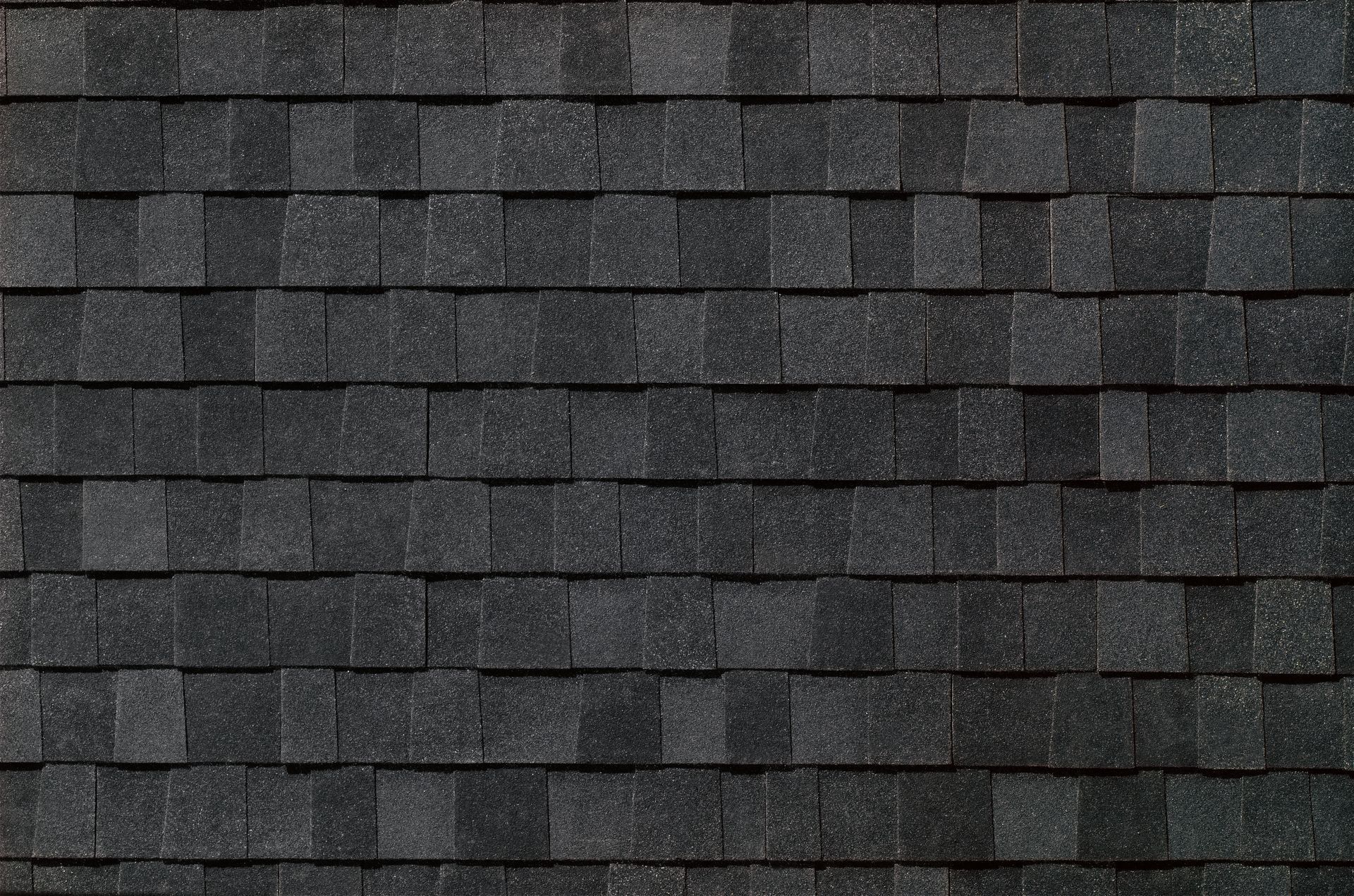 Close-up of dark gray asphalt roof shingles with a repetitive horizontal pattern.