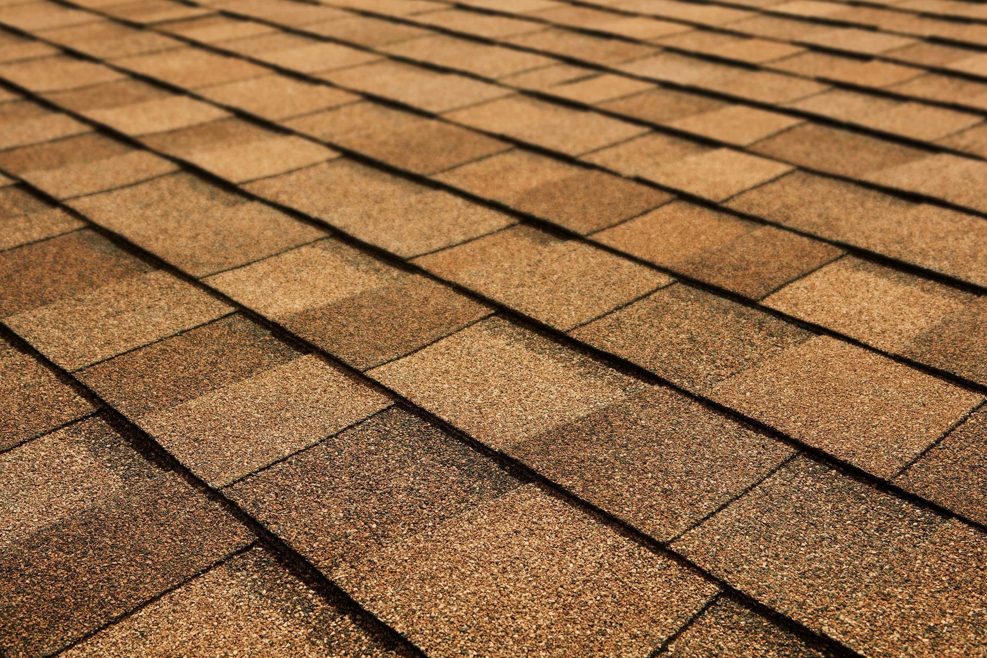 Close-up of brown asphalt roof shingles in diagonal rows