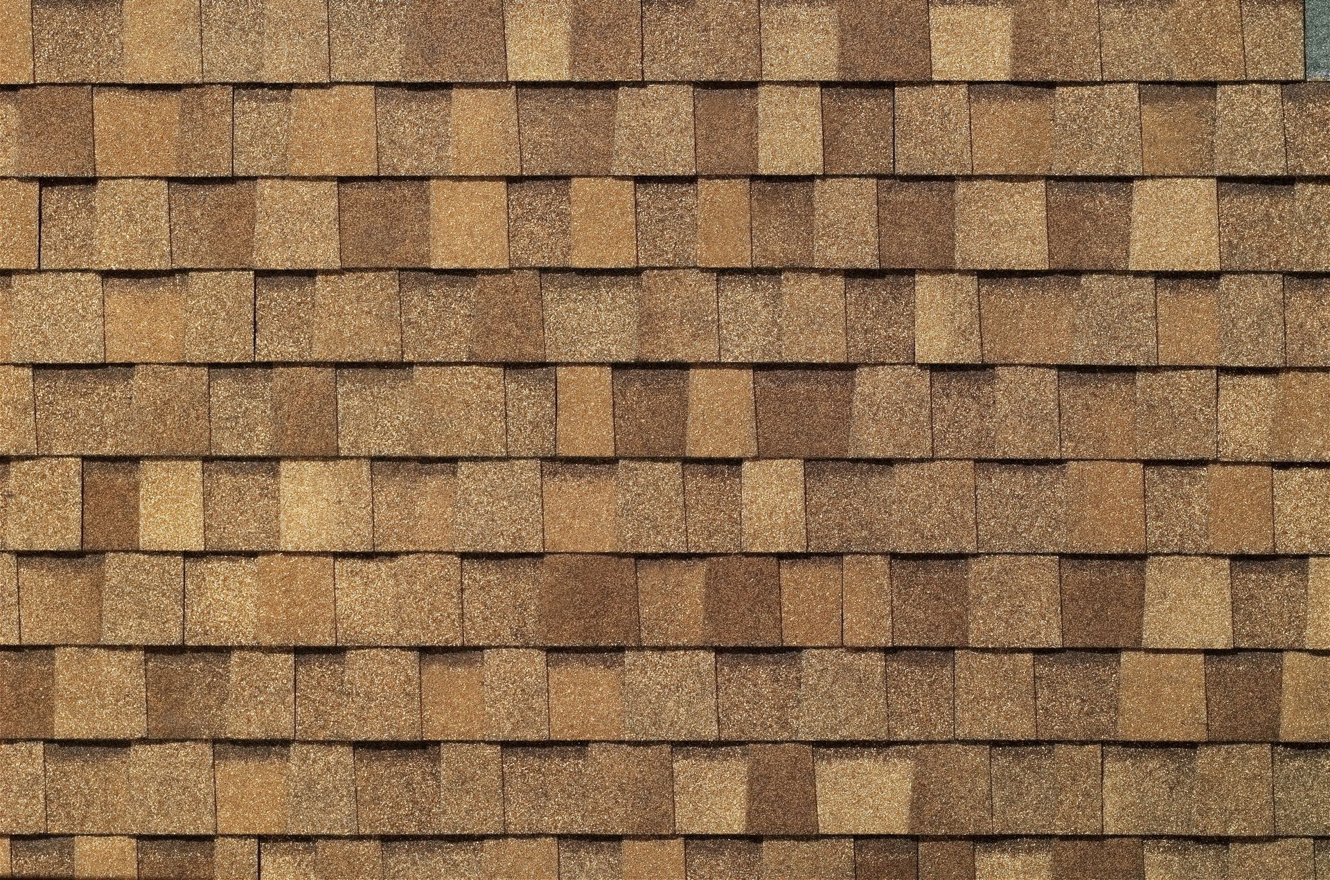 Close-up of overlapping brown wooden roof shingles with a textured, weathered surface.