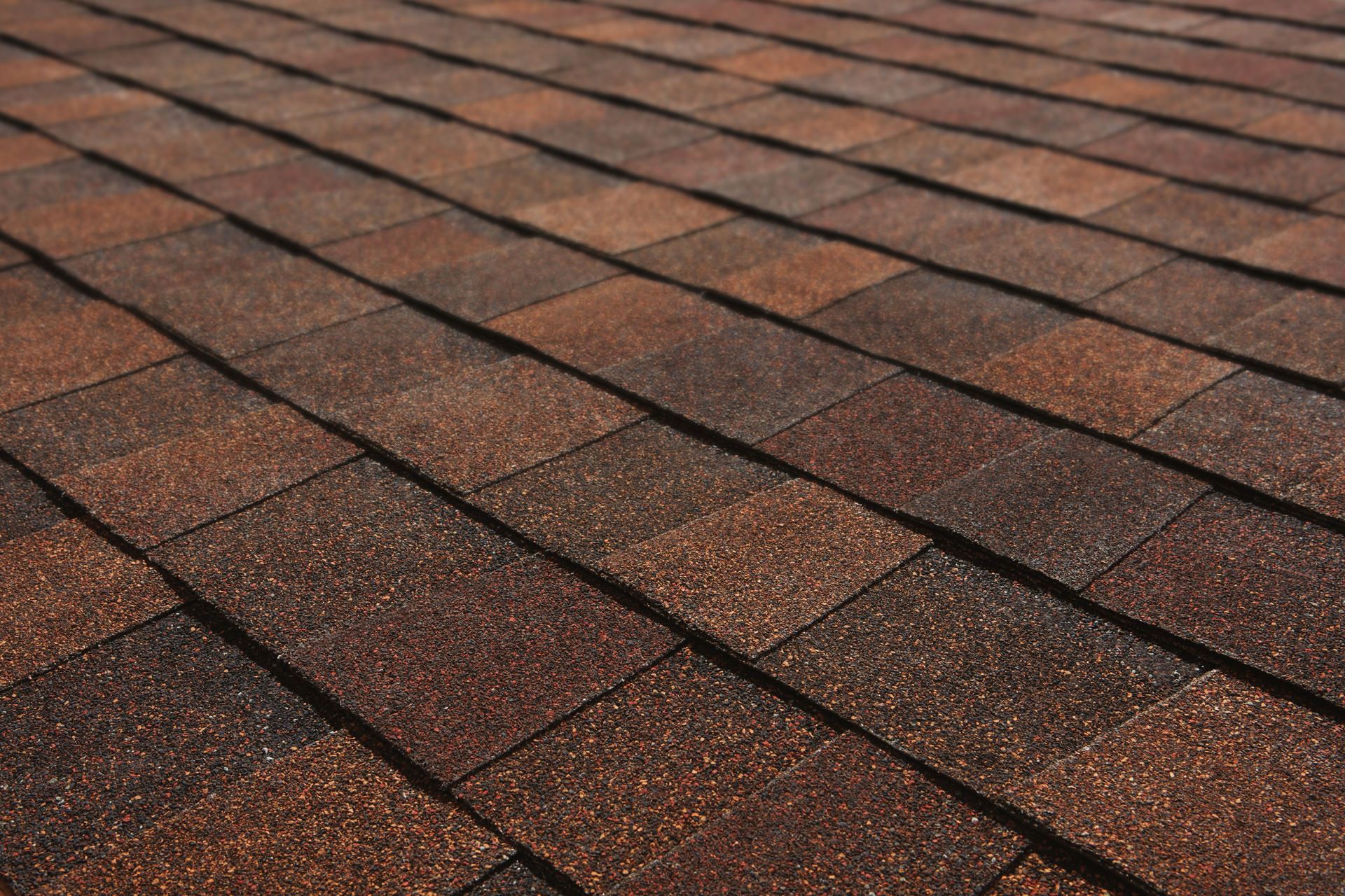 Close-up of brown asphalt roof shingles with a textured, diagonal pattern