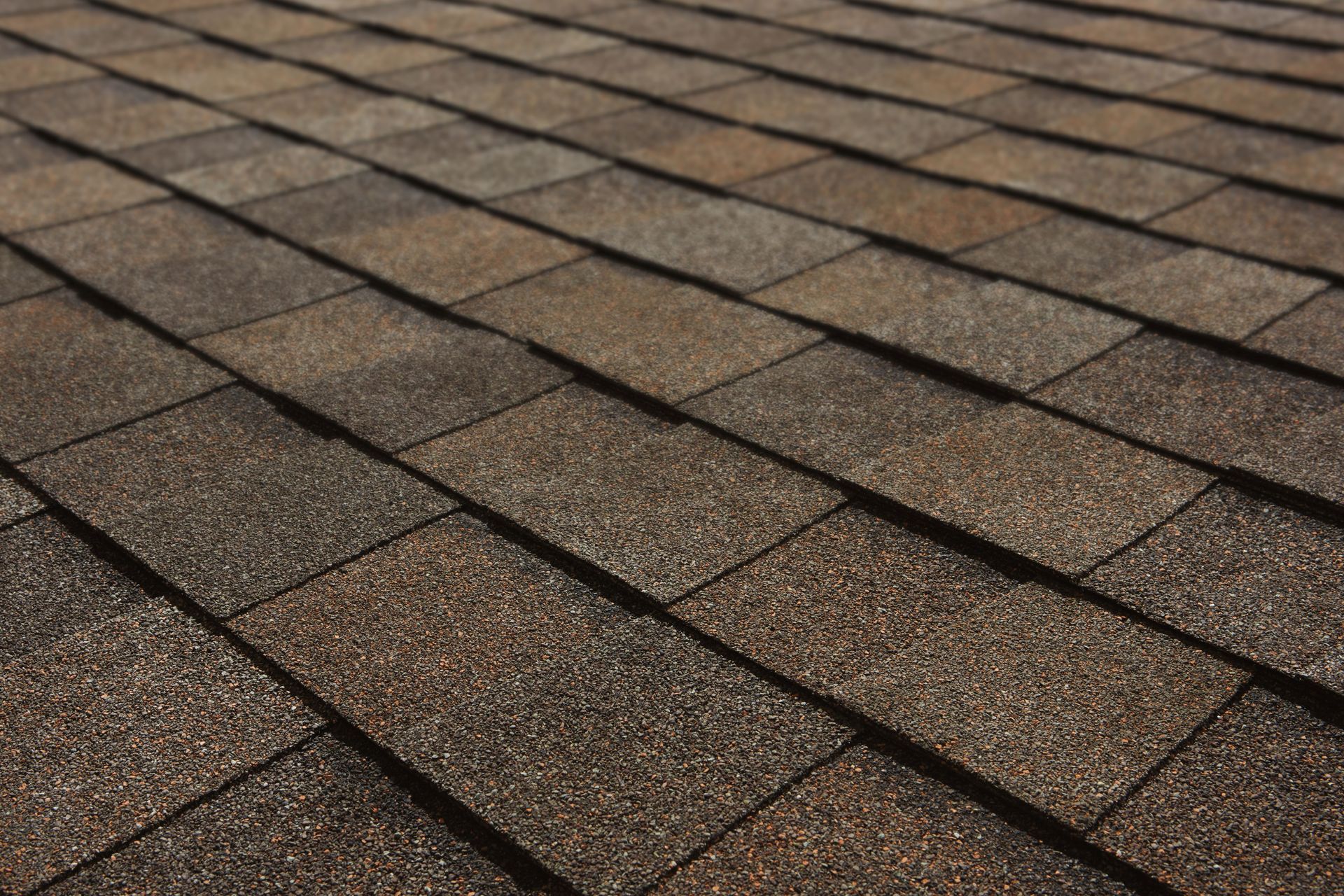 Close-up of a brown shingled roof with rows of textured asphalt shingles