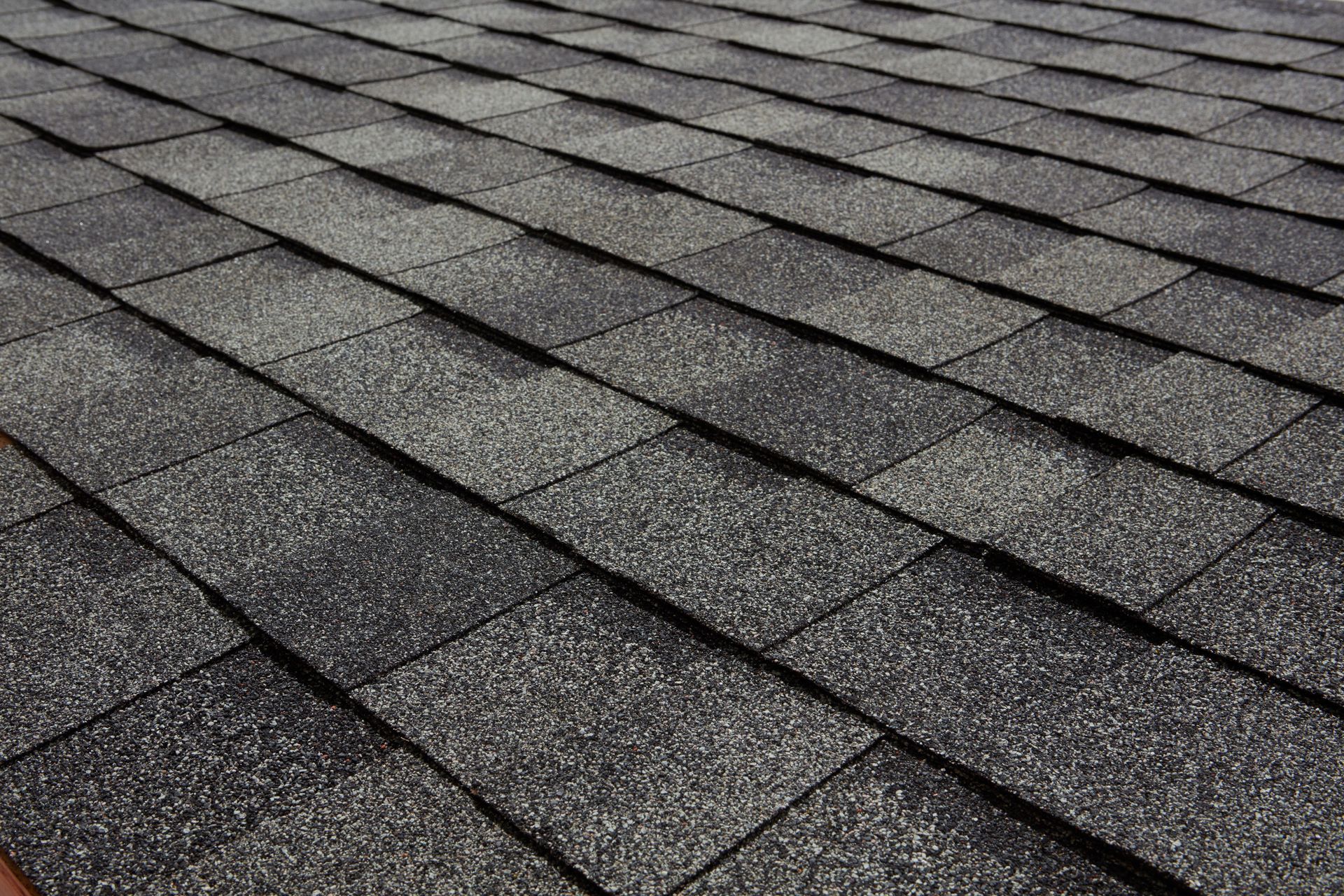 Close-up of gray asphalt roof shingles in overlapping rows