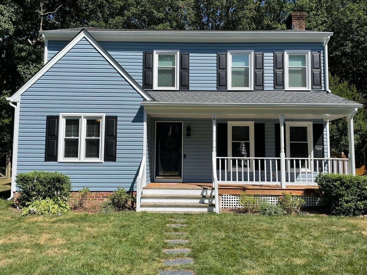 Blue two-story house with white trim and a front porch, viewed from the yard