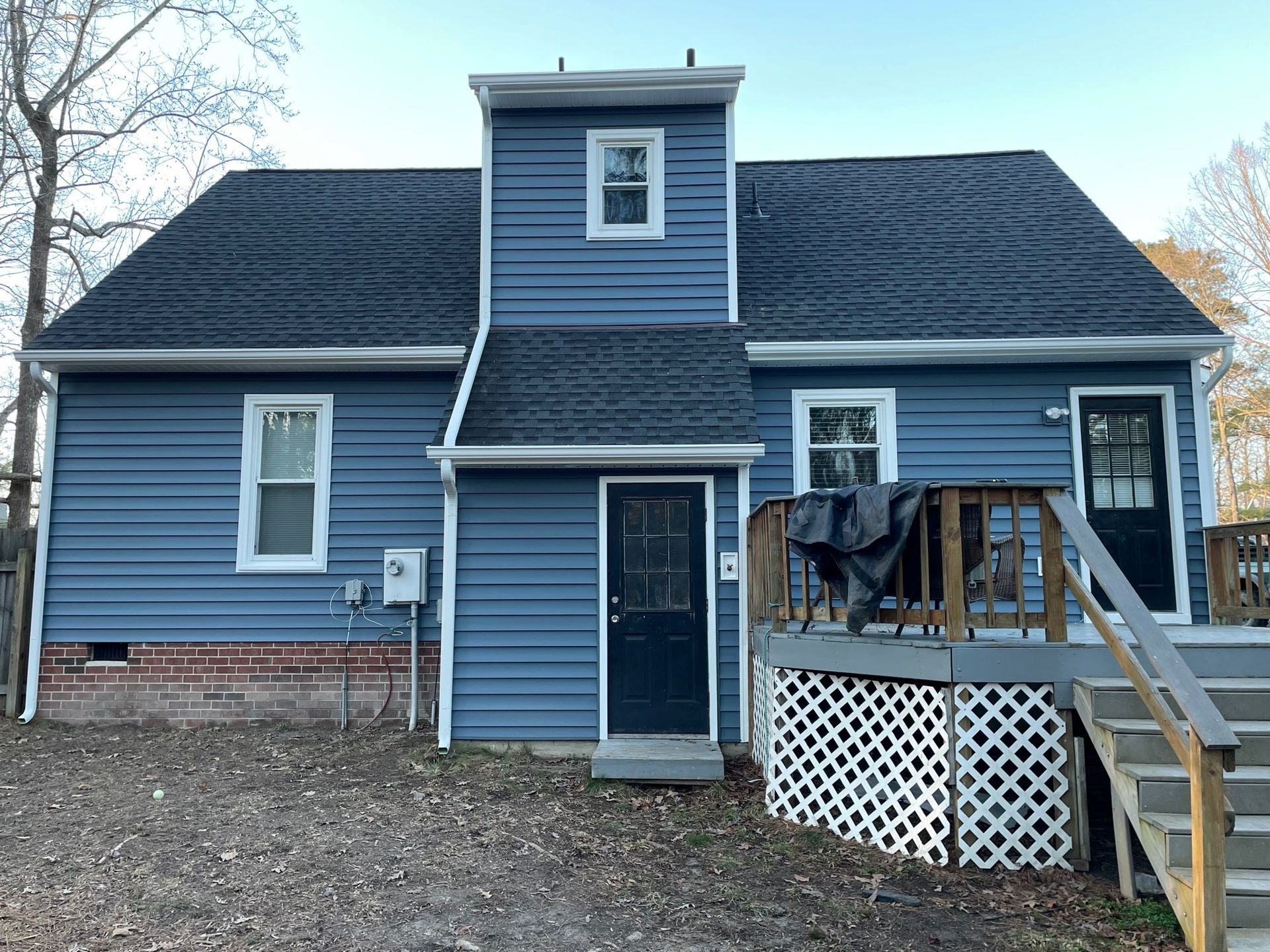 Blue house exterior with a front porch, stairs, and white lattice skirting