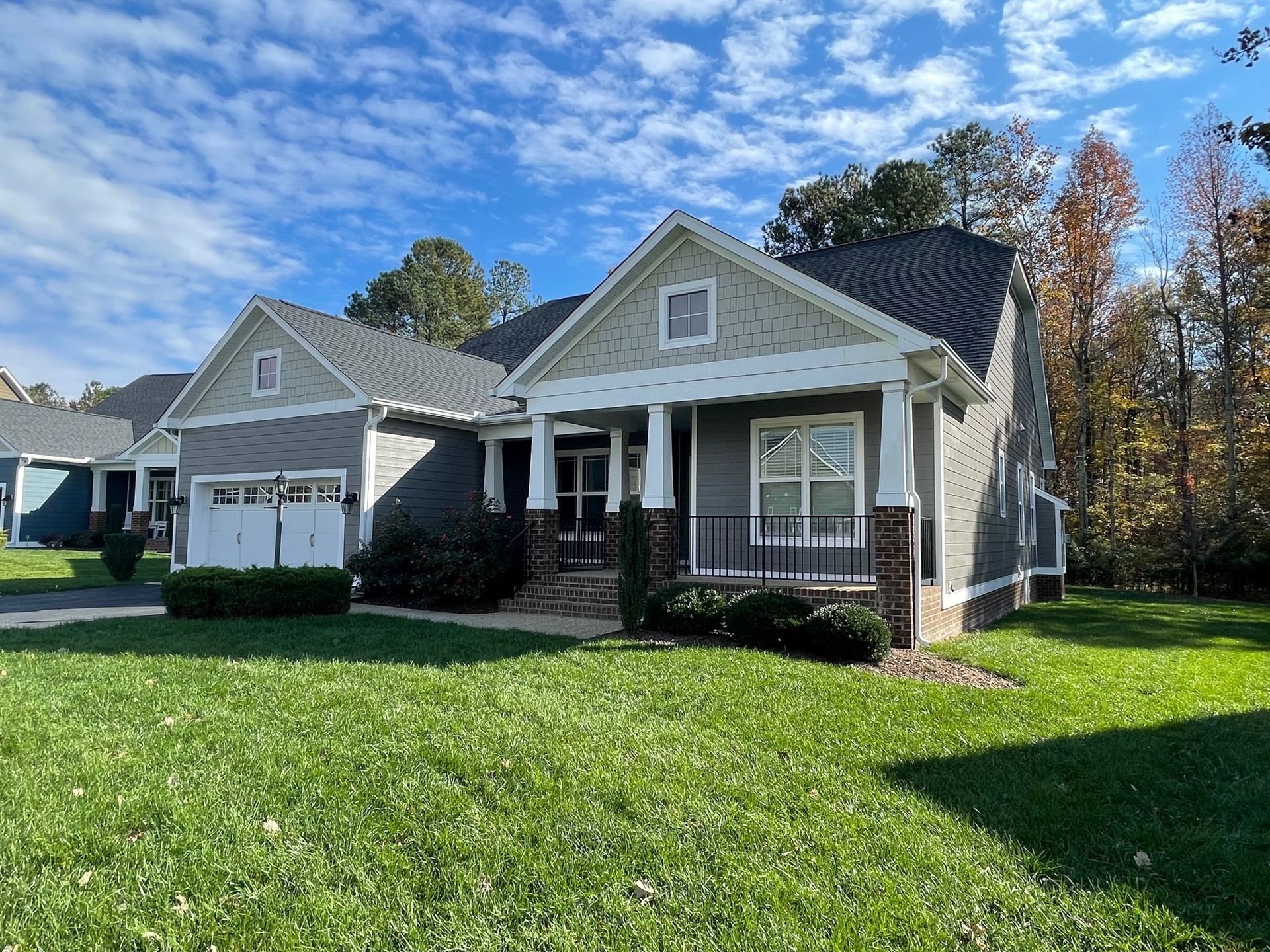 Suburban house with a front porch, white trim, and a green lawn on a sunny day