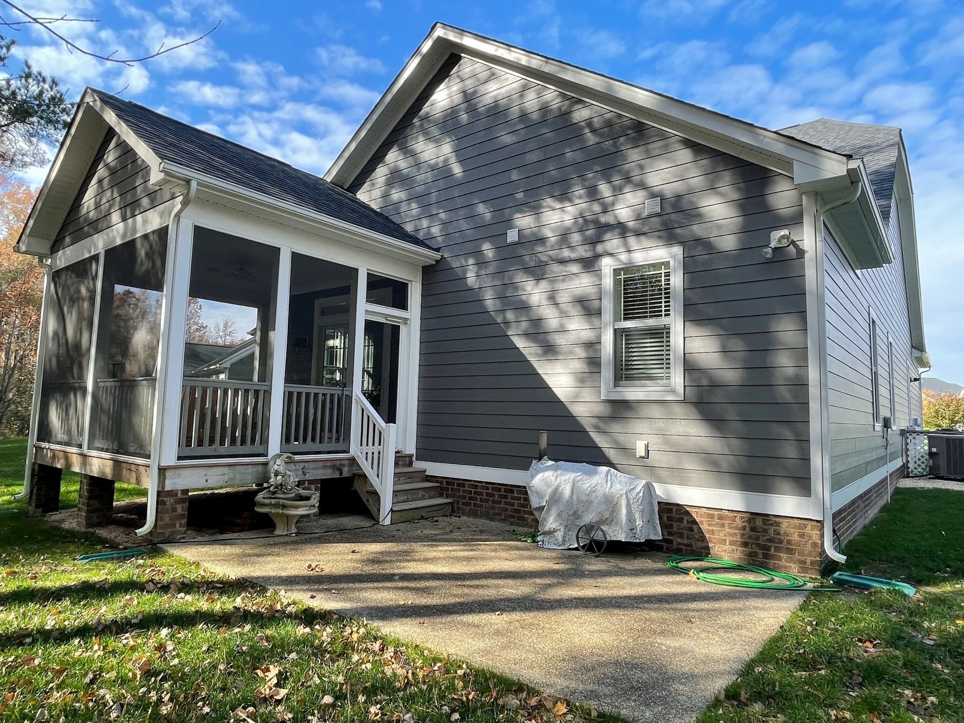 Gray house exterior with small front porch, white trim, and a concrete walkway in a grassy yard