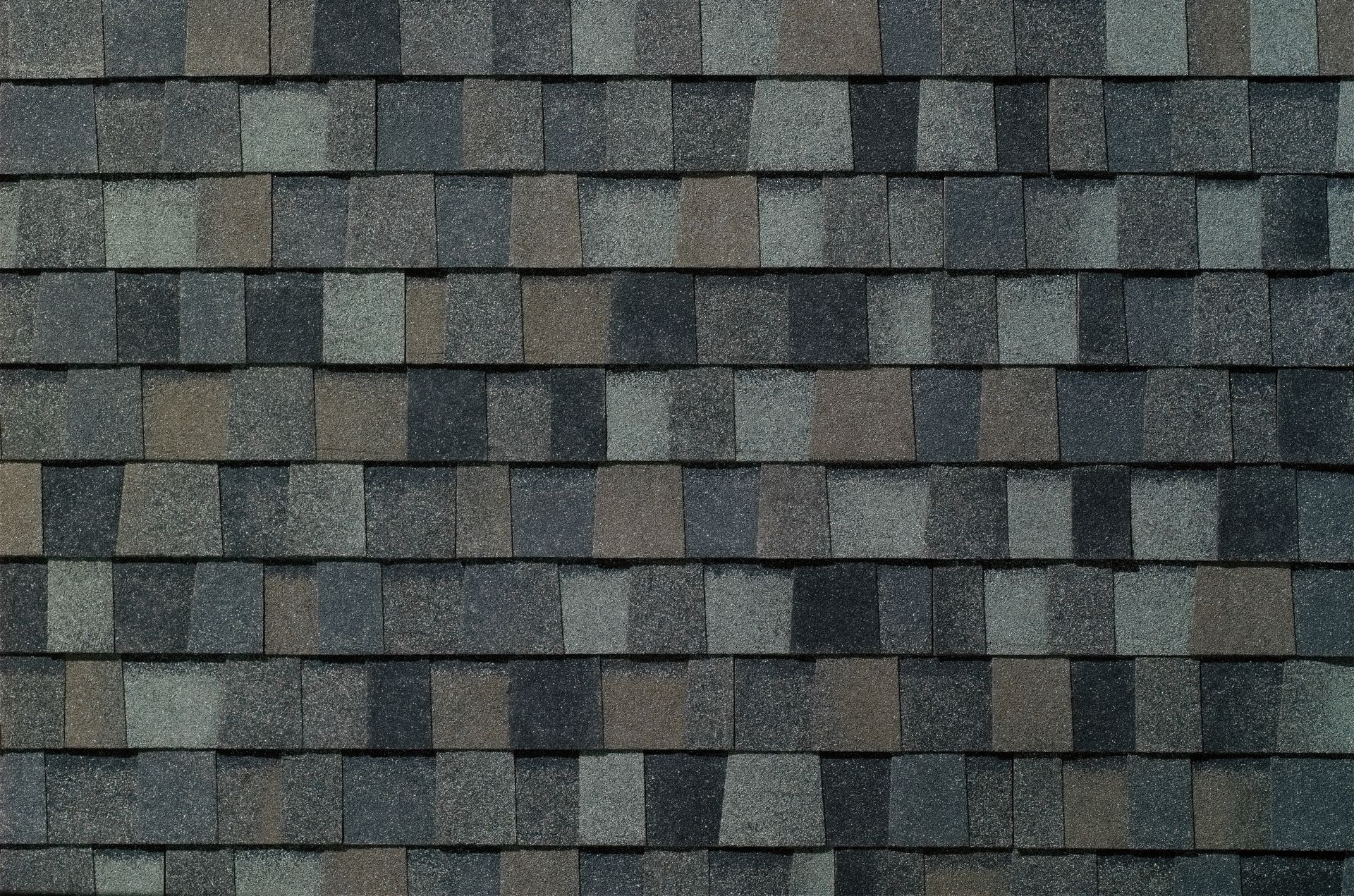 Close-up of weathered gray and dark green roof shingles arranged in a staggered pattern